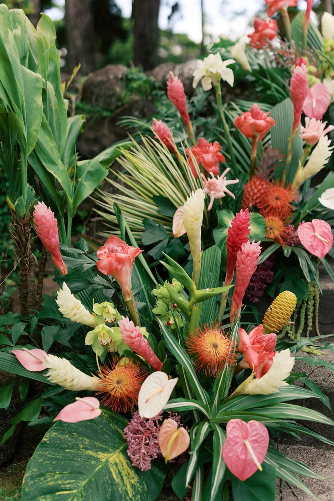 Colorful floral arrangement with various tropical flowers and green foliage.
