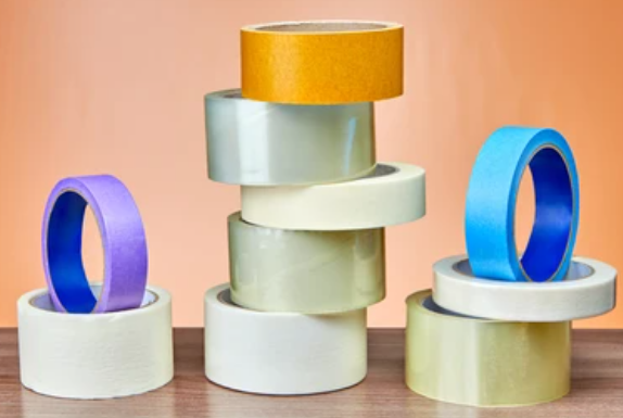 Stacked rolls of colorful masking tape on a wooden surface