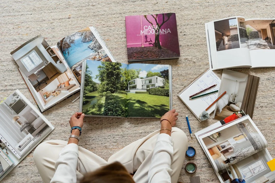 A flat lay of interior design materials including paint swatches, a small bowl of paint, fabric swatches, a decorative bowl, a brass door knob, and various textured surfaces.