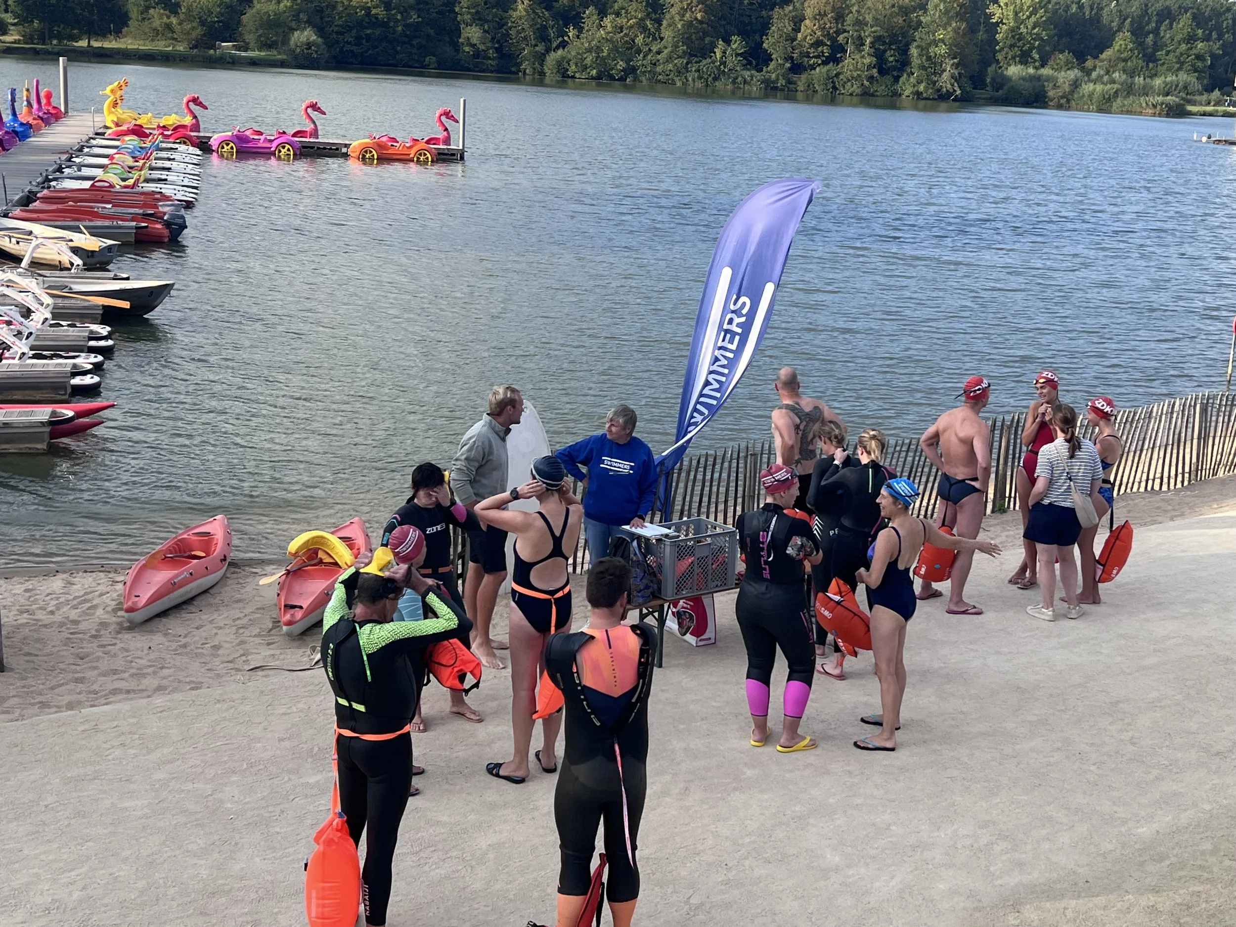 Een groep zwemmers en instructeurs verzamelt zich aan de oever van de Gavers