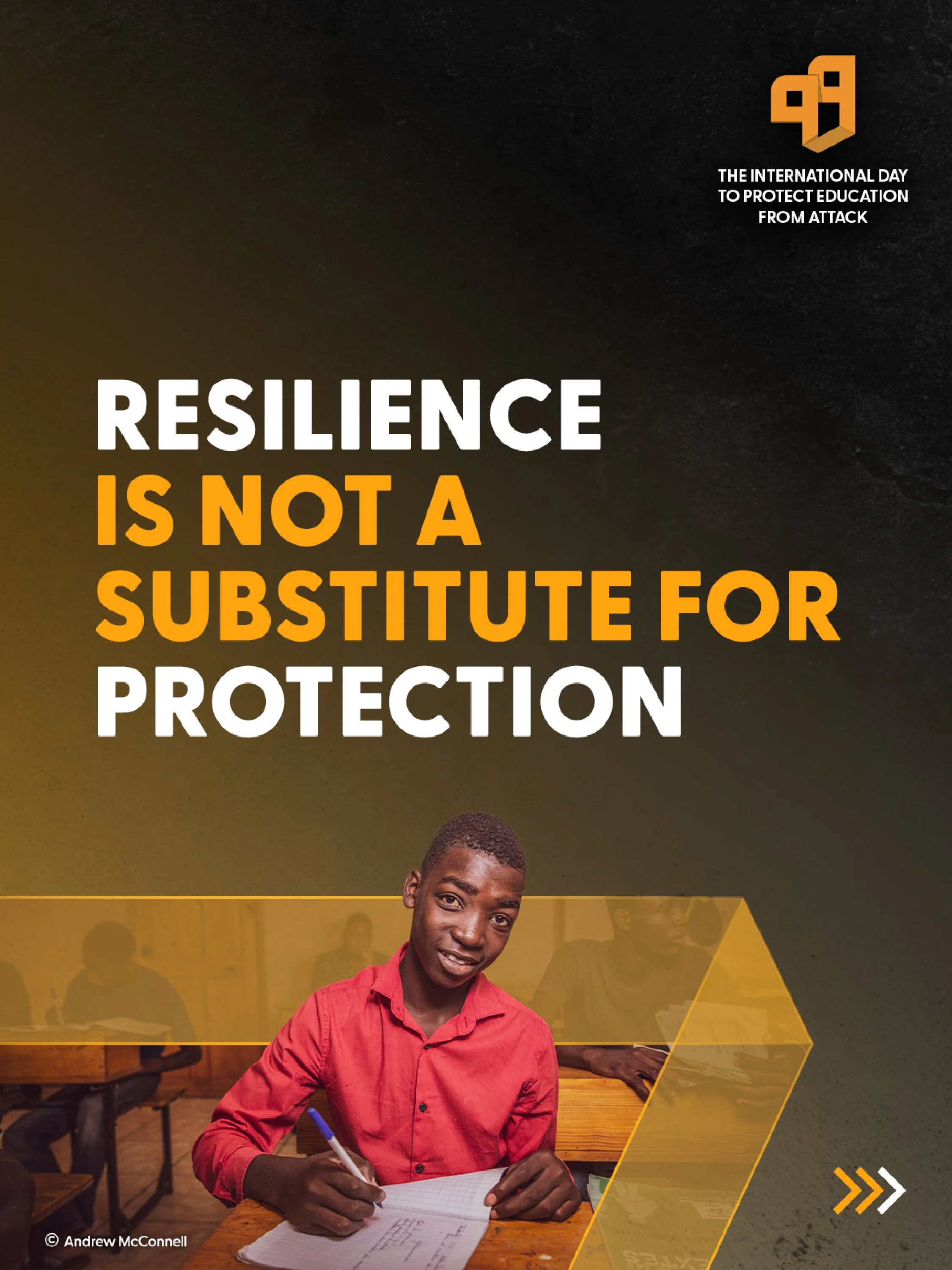 A young man in a red shirt sitting at a wooden table in a classroom, writing in a notebook with a blue pen. There are other students in the background, some sitting at tables and some standing, with a dark wall and yellow geometric shapes overlaying the image. The text on the top right mentions the international day to protect education from attack and the phrase 'Resilience is not a substitute for protection.'