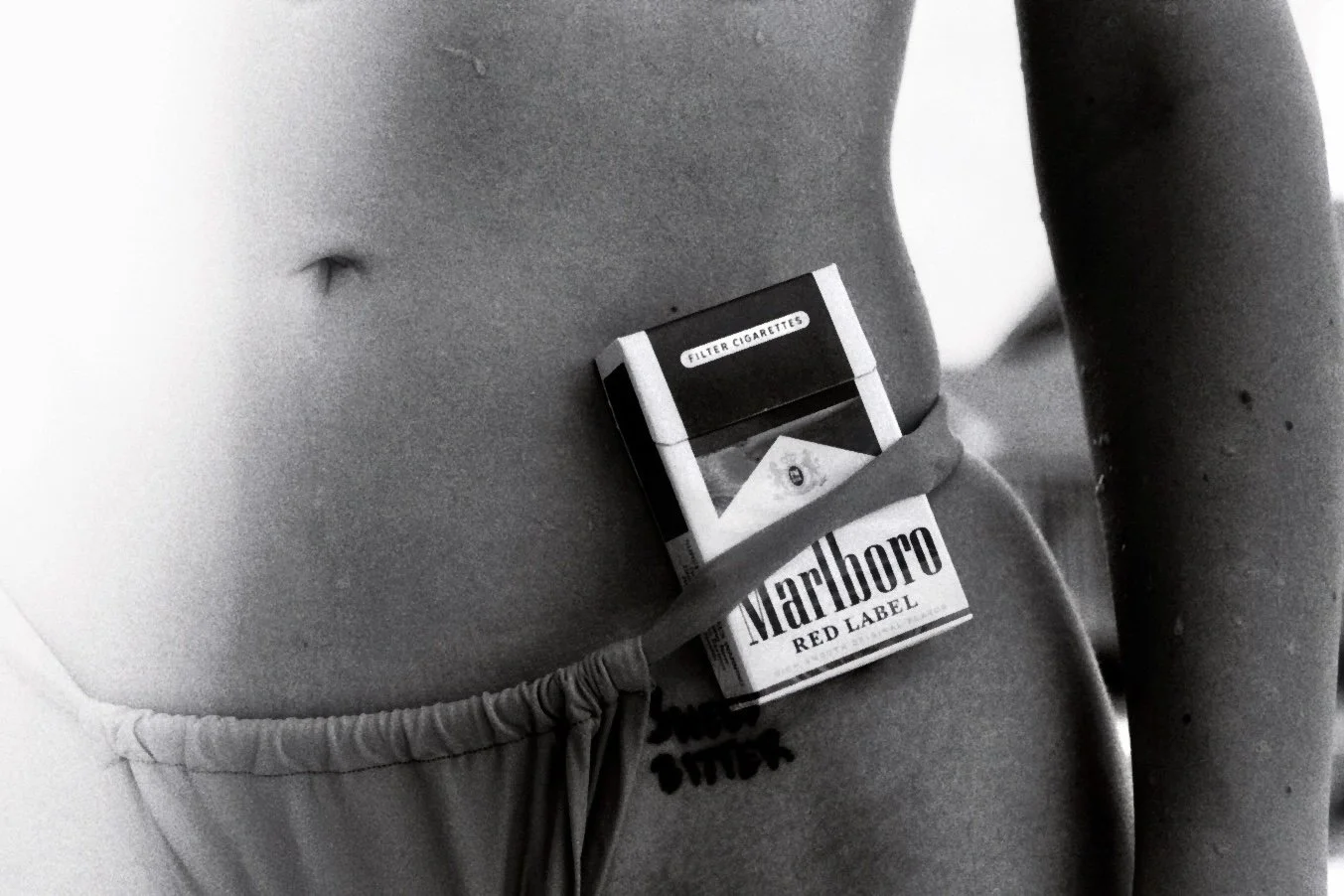 Nahaufnahme eines Oberkörpers einer Person mit einem Marlboro Zigaretten-Pack in der Nähe des Bauchnabels.