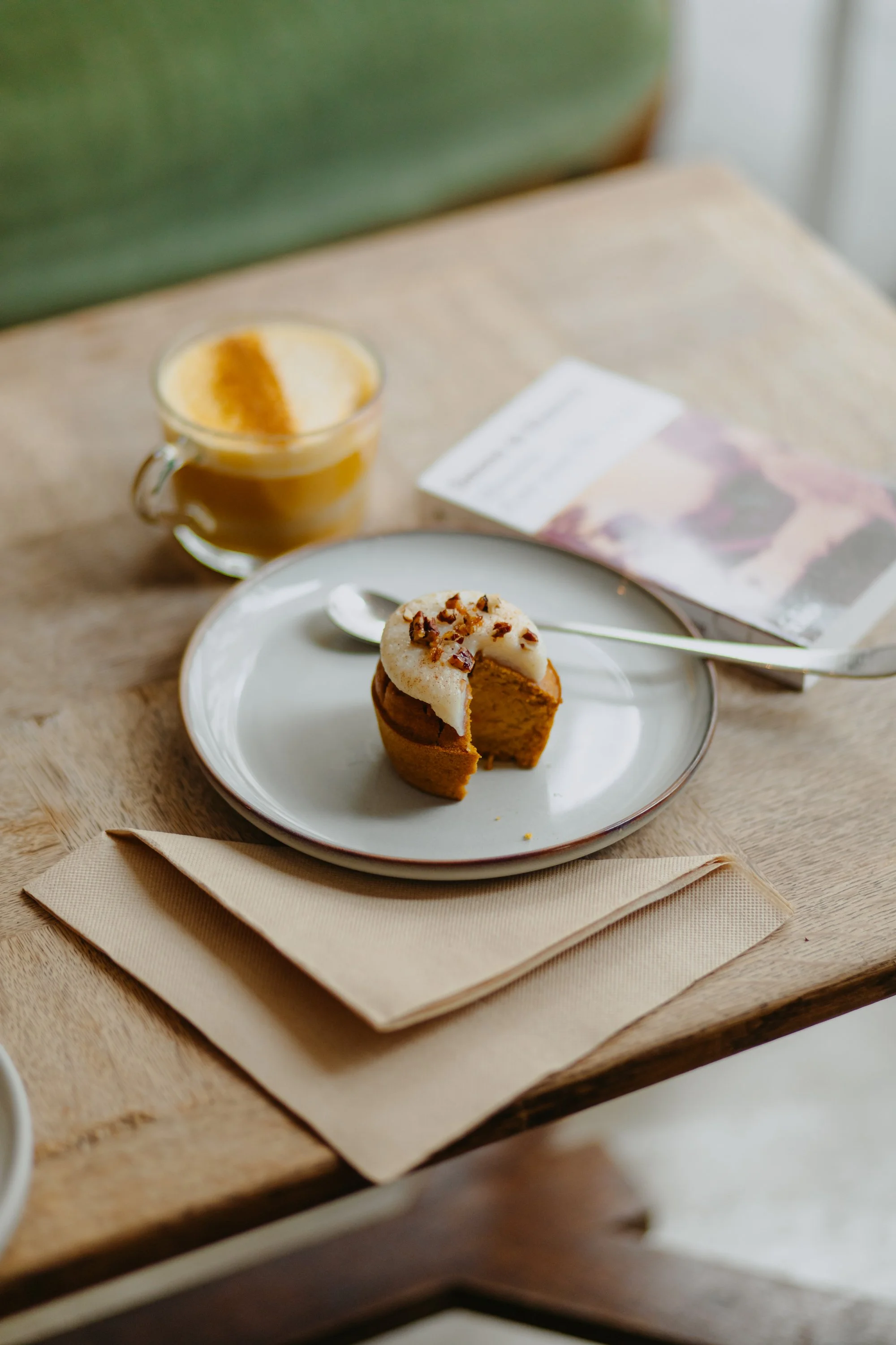 Gâteau à la farine de patate douce, glacé avec des noix coupées en garniture, accompagné d'une tasse de café avec de la crème et de la cannelle en surface.