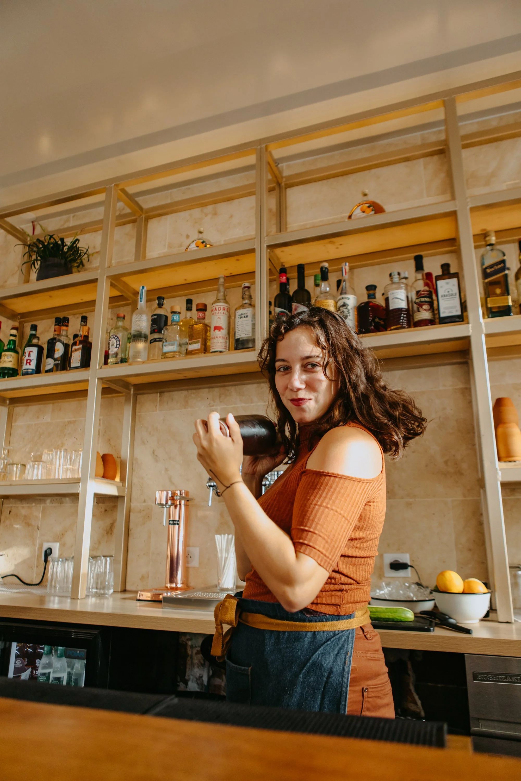 Femme souriante dans un bar ou un restaurant, tenant une bouteille