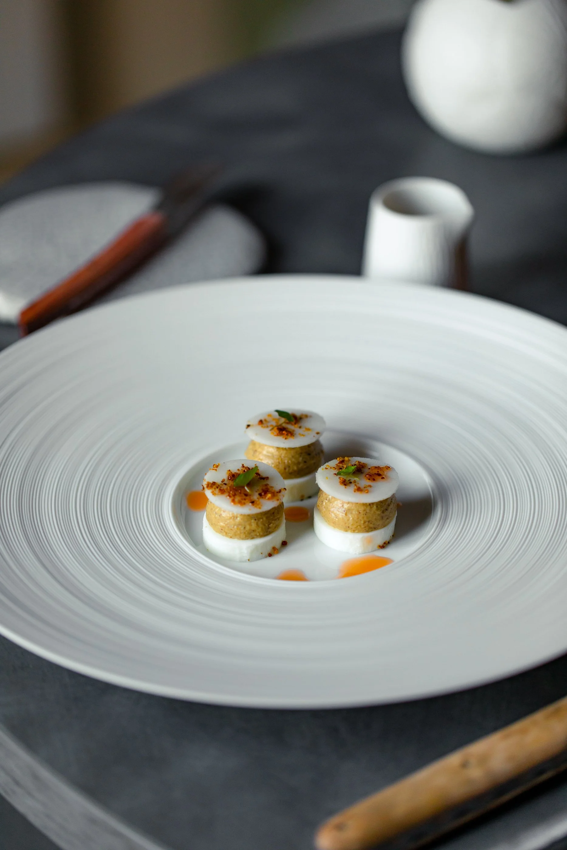 Assiette de tapas avec trois rondelles de fromages blanc et galette de pommes de terre, garnies de fines herbes et épices, servies avec une sauce en petits gouttes.