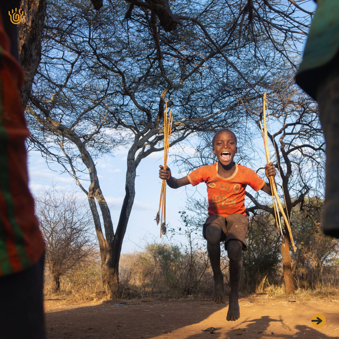 A picture of an excited Hadzabe Kids holding his bow and arrows on both hands