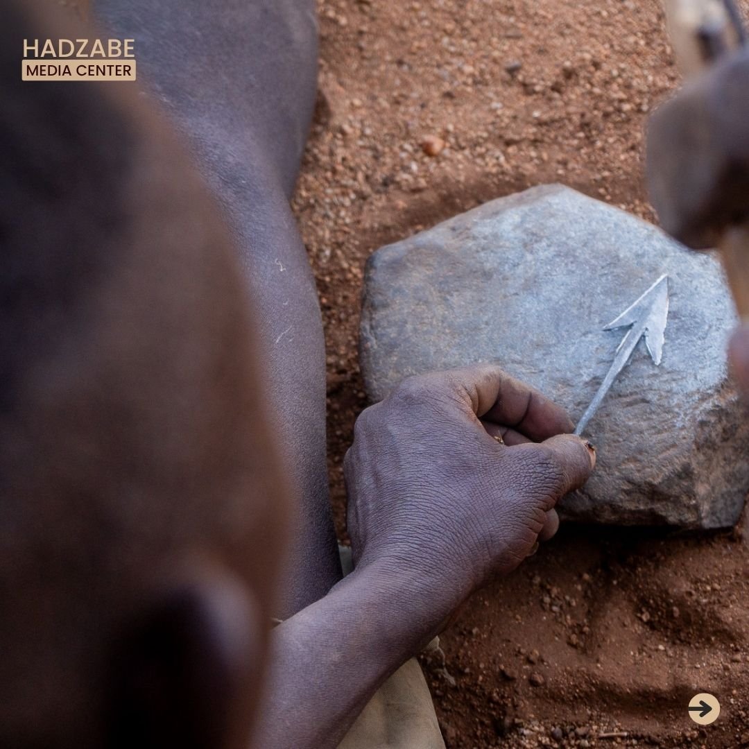 A picture of a man hammering an arrow head of a stone