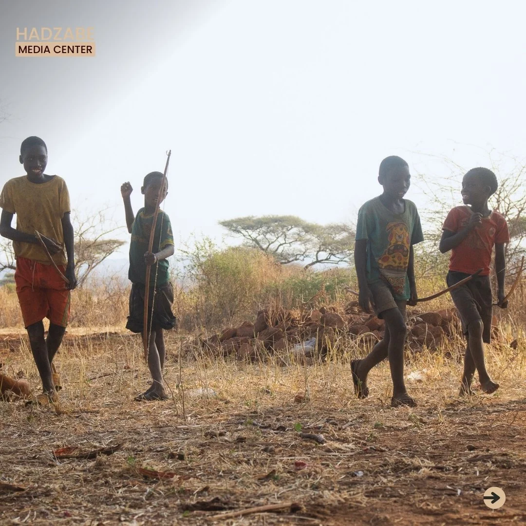 A picture of four Hadzabe walking towards something while holding their bow and arrows