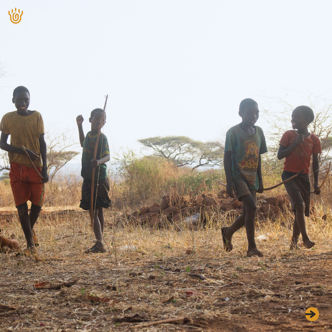 A picture of four Hadzabe walking towards something while holding their bow and arrows