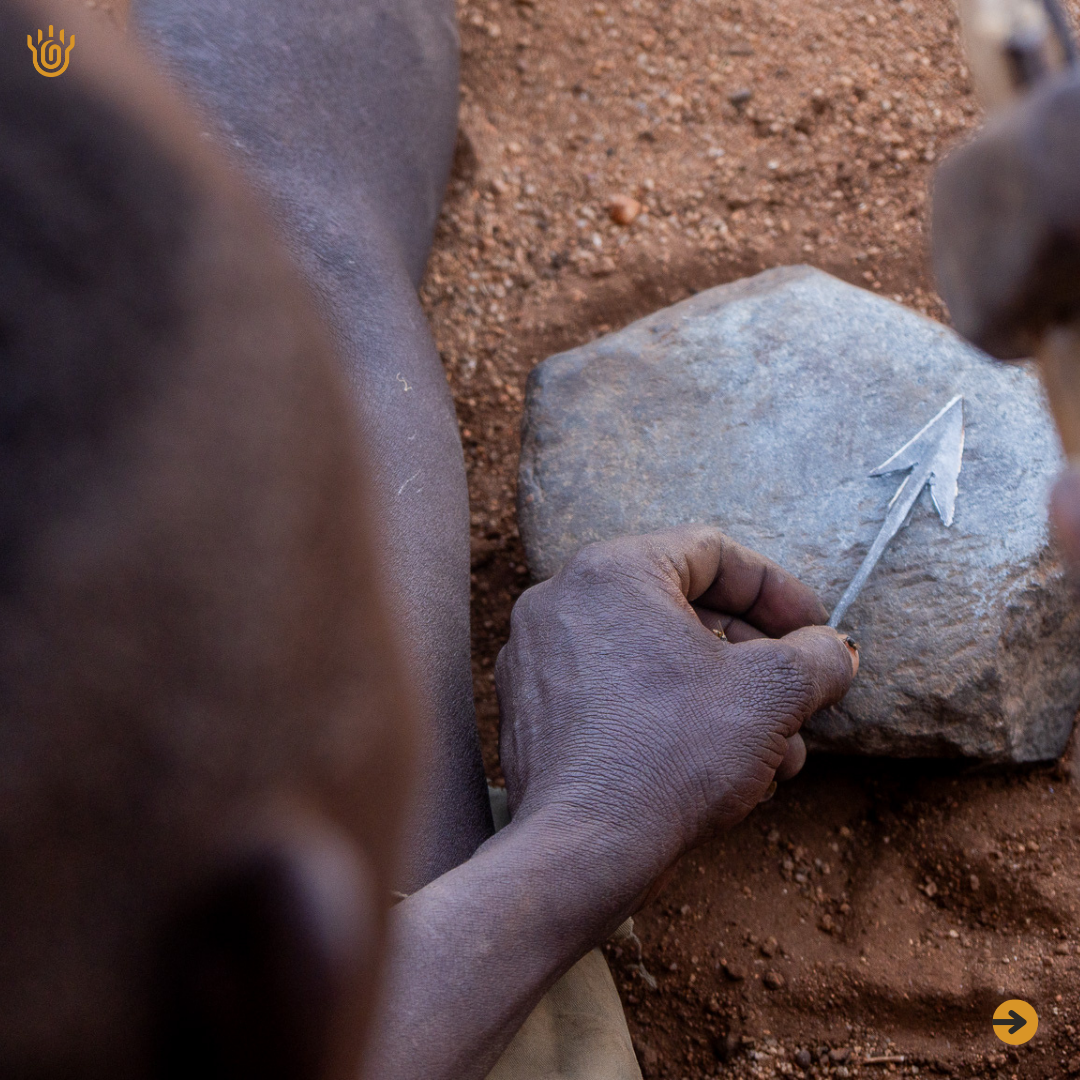 A picture of a man hammering an arrow head of a stone