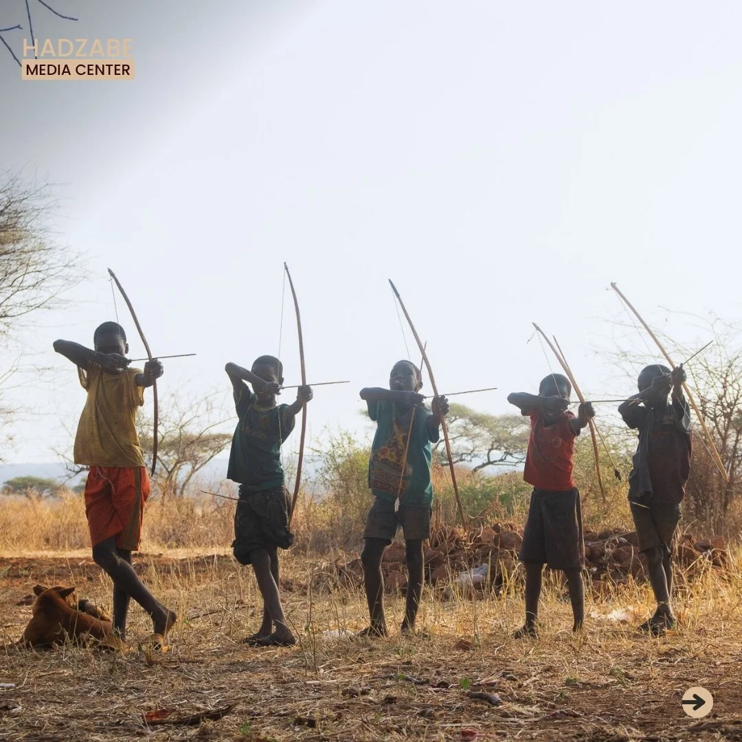 A front view picture showing a Hadzabe kids in a line holding their bow and arrows