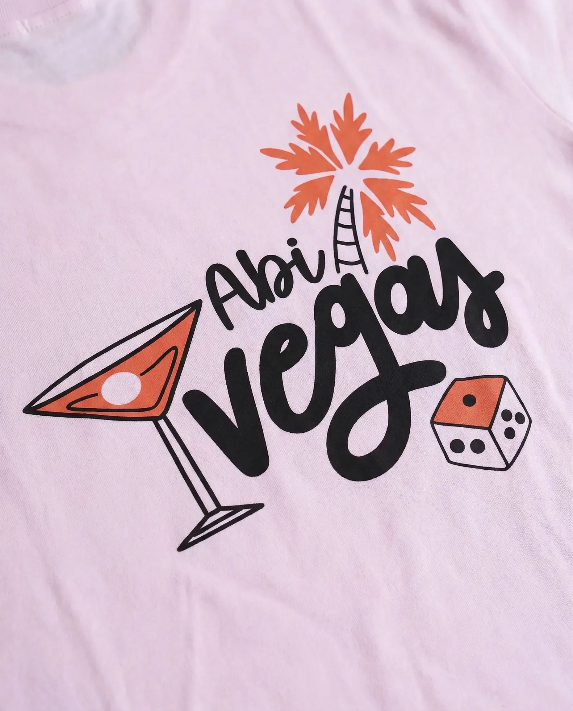 Ein T-Shirt mit dem Schriftzug "Ahoi Vogais" in Schwarz, einem orangenen Cocktailglas, einer orangenen Palme und einem Würfel.