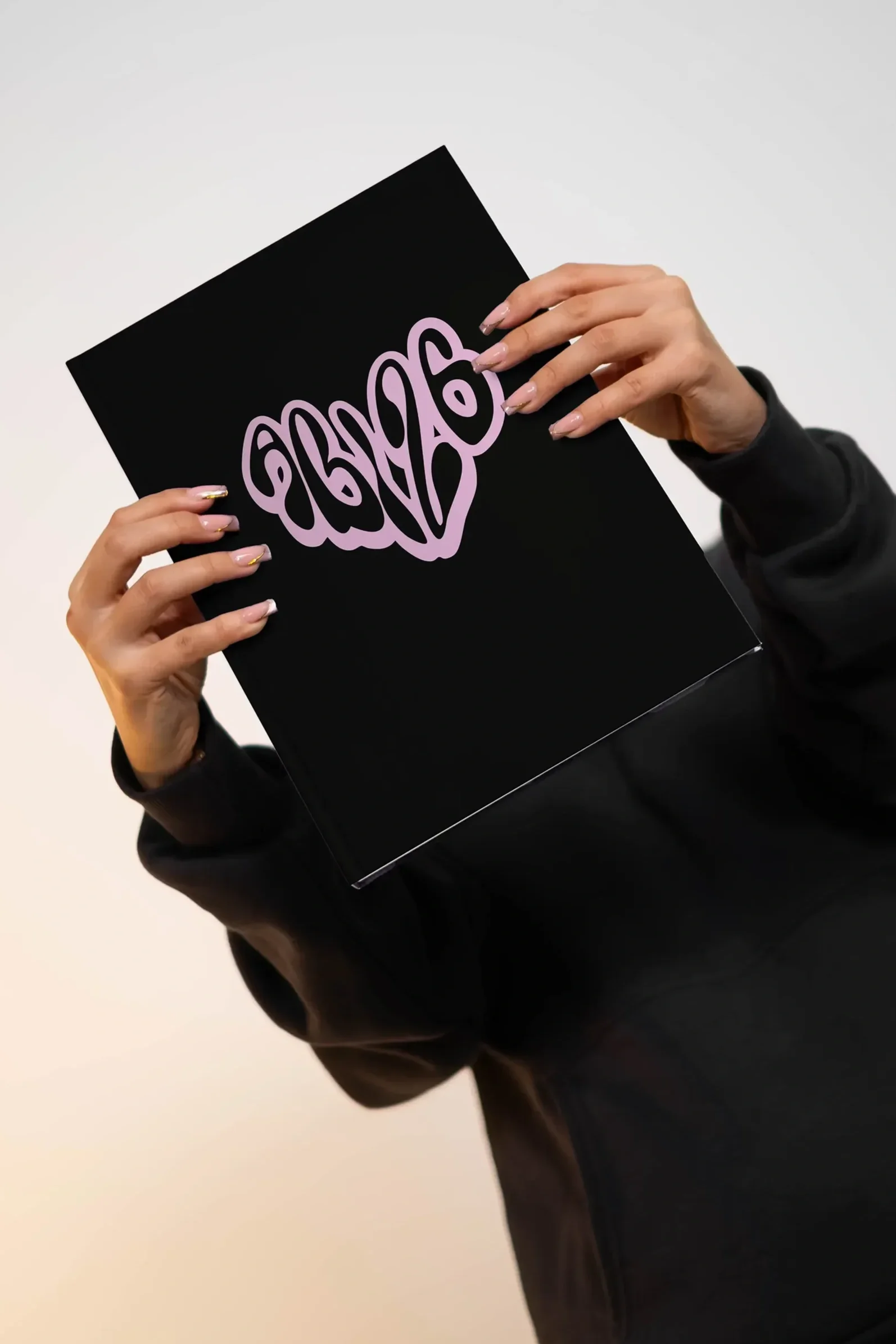 Person hält ein schwarzes Buch mit einer lilafarbenen, kalligrafischen Aufschrift