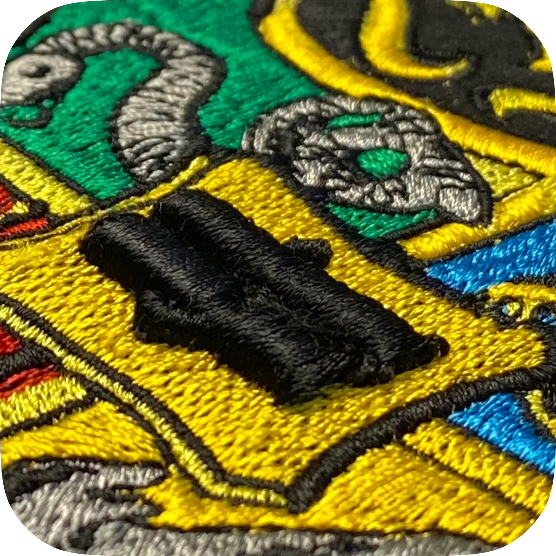 Detaillierte Nahaufnahme eines Stickmusters mit einem schwarzen Herz, bunten Flächen und schwarzen Konturen.