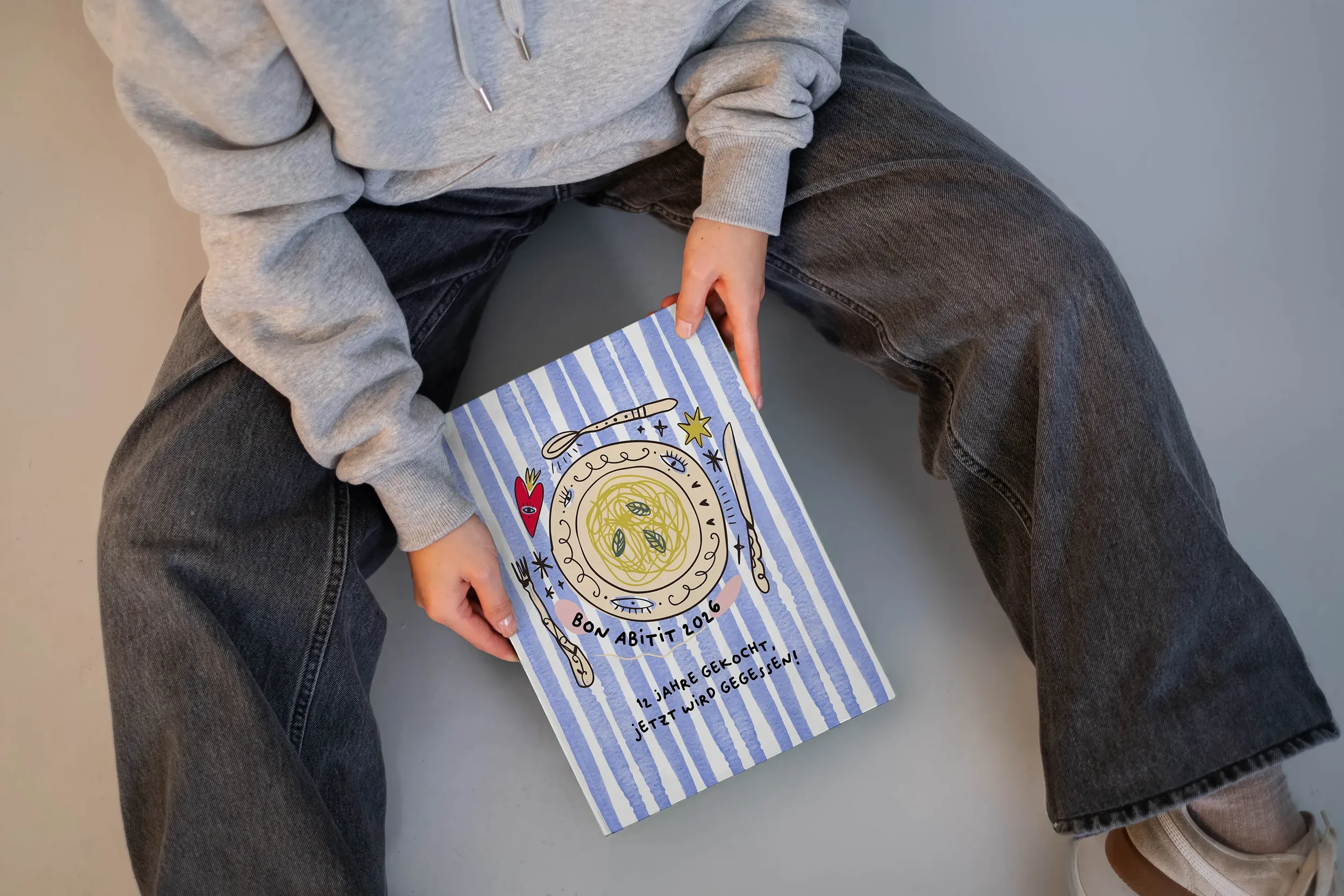 Person sitzt auf dem Boden und hält eine Karte mit Kaffee-Illustration, blauer Streifen-Hintergrund, Text in Deutsch.