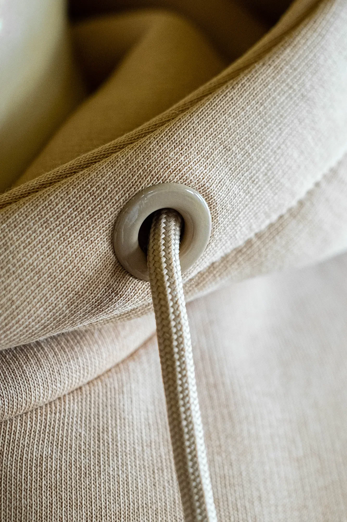 Nahaufnahme eines beige-leinenen Sofas mit einer weißen Schnur, die durch eine Öse geführt wird.