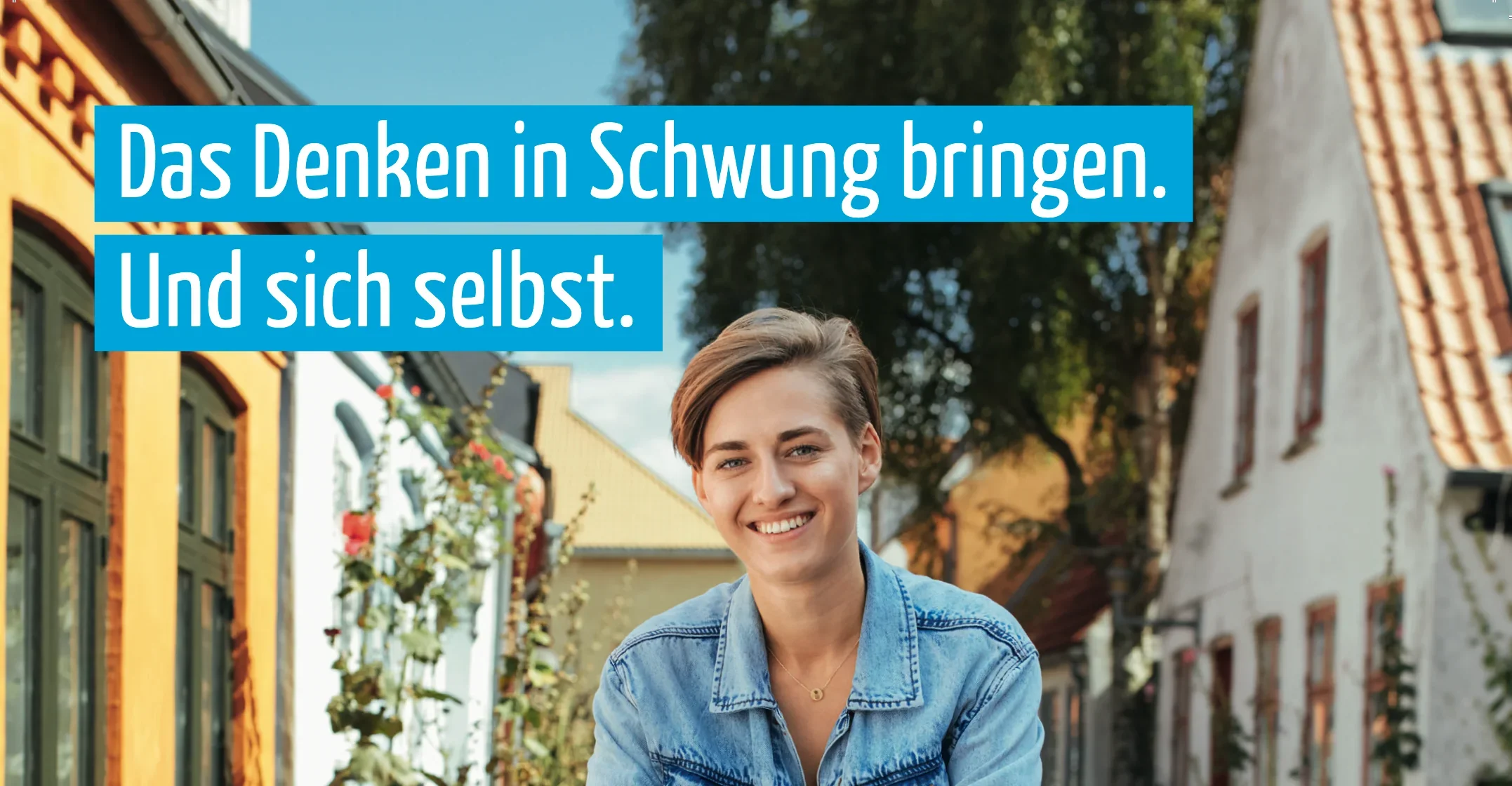 Eine lächelnde junge Frau vor bunten Häusern in einer Straße, mit einem Spruch auf blauer Hintergrund: 'Das Denken in Schwung bringen. Und sich selbst.'