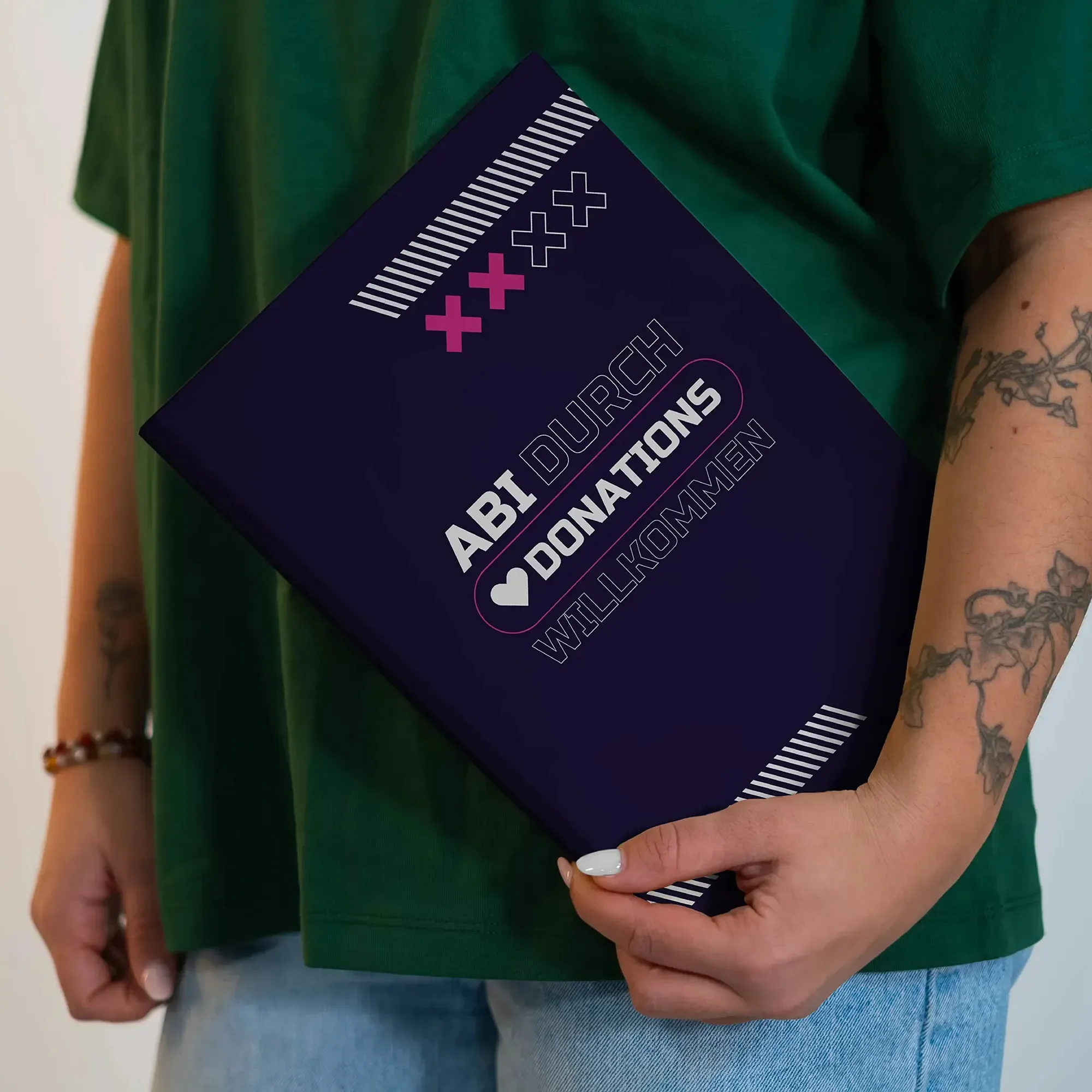 Eine Person hält eine dunkle Aktentasche, auf der steht: 'ABT DURCH DONATIONS WILLKOMMEN', mit einem Herzsymbol.