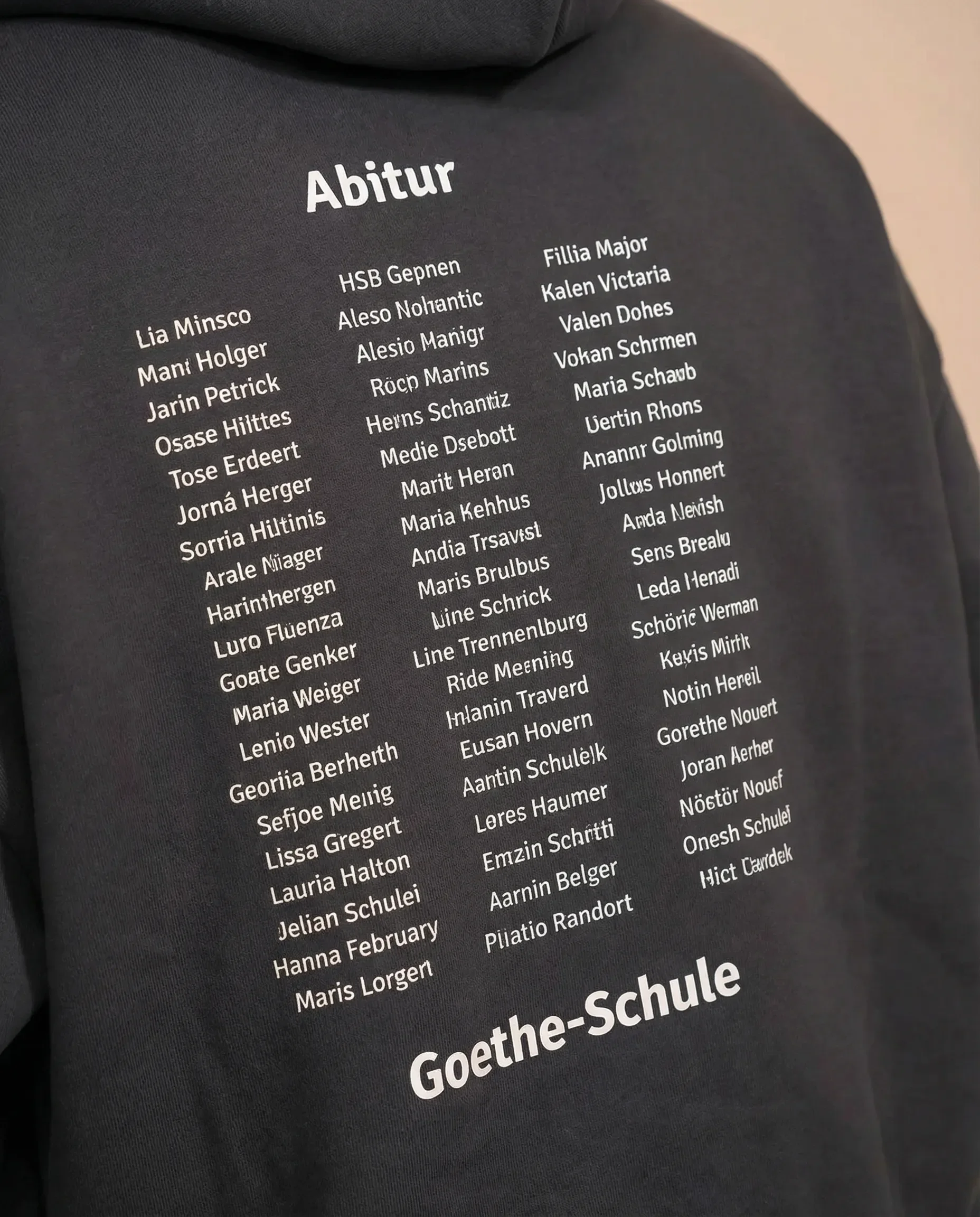 Liste der Namen in weißer Schrift auf schwarzem T-Shirt, mit Überschrift 'Abitur' und 'Goethe-Schule' am unteren Rand.