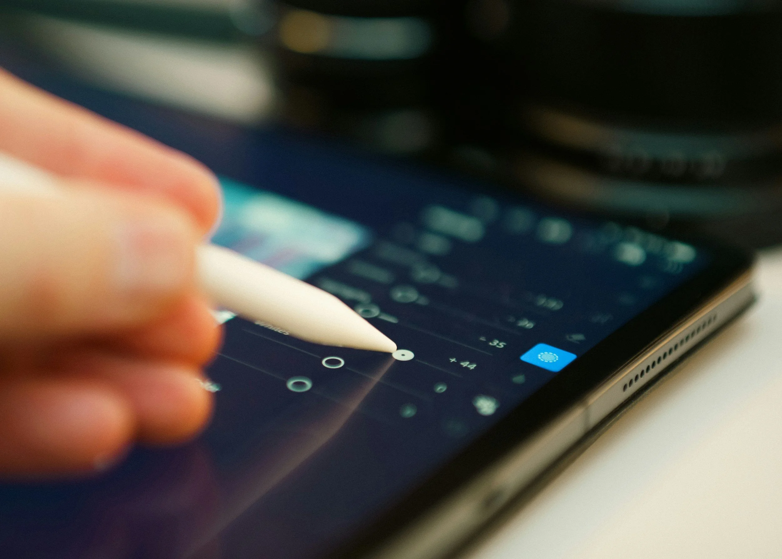Close-up of a person using a stylus on a tablet to create or edit a digital chart or graph, with a blurred background.