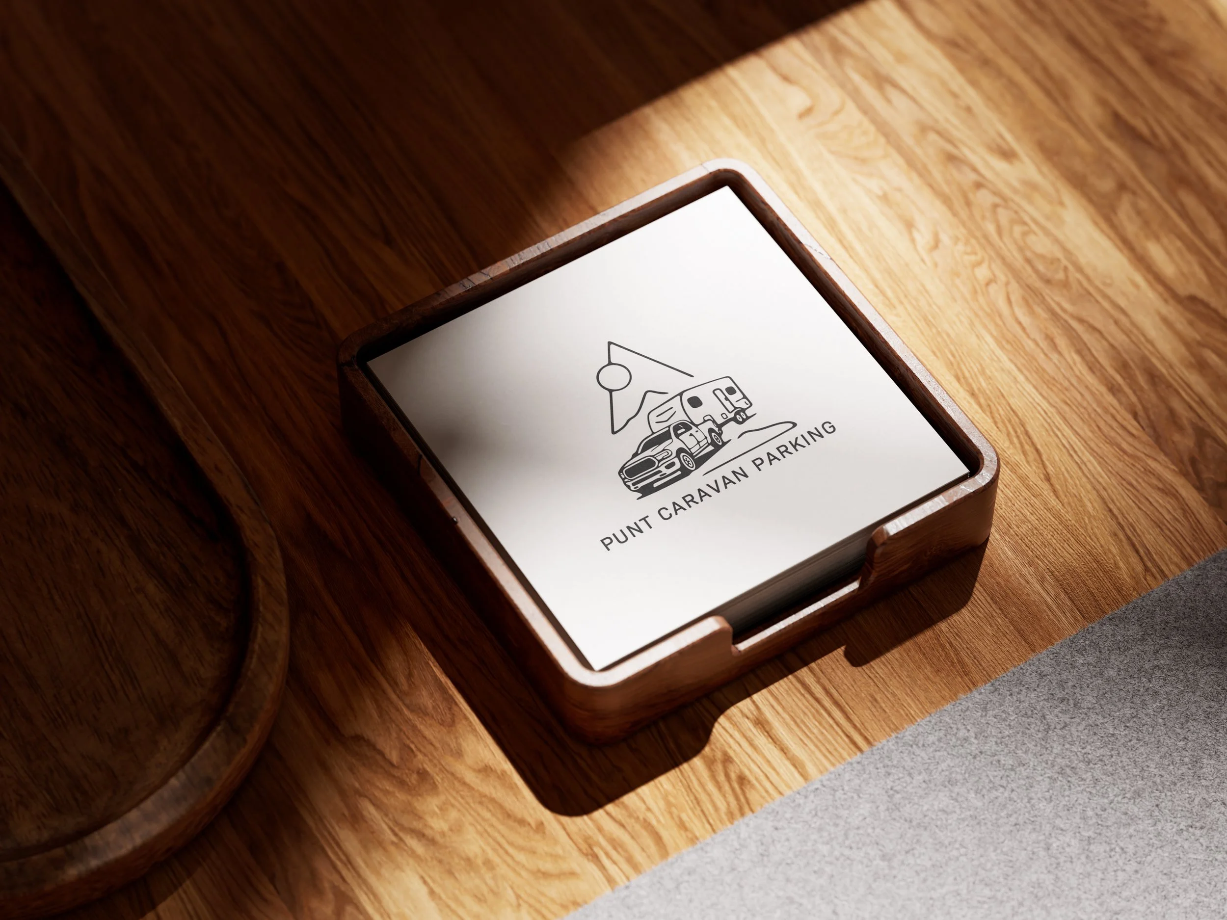 Wooden sign with a black and white drawing of a caravan and a mountain, labeled "PUNT CARAVAN PARKING".