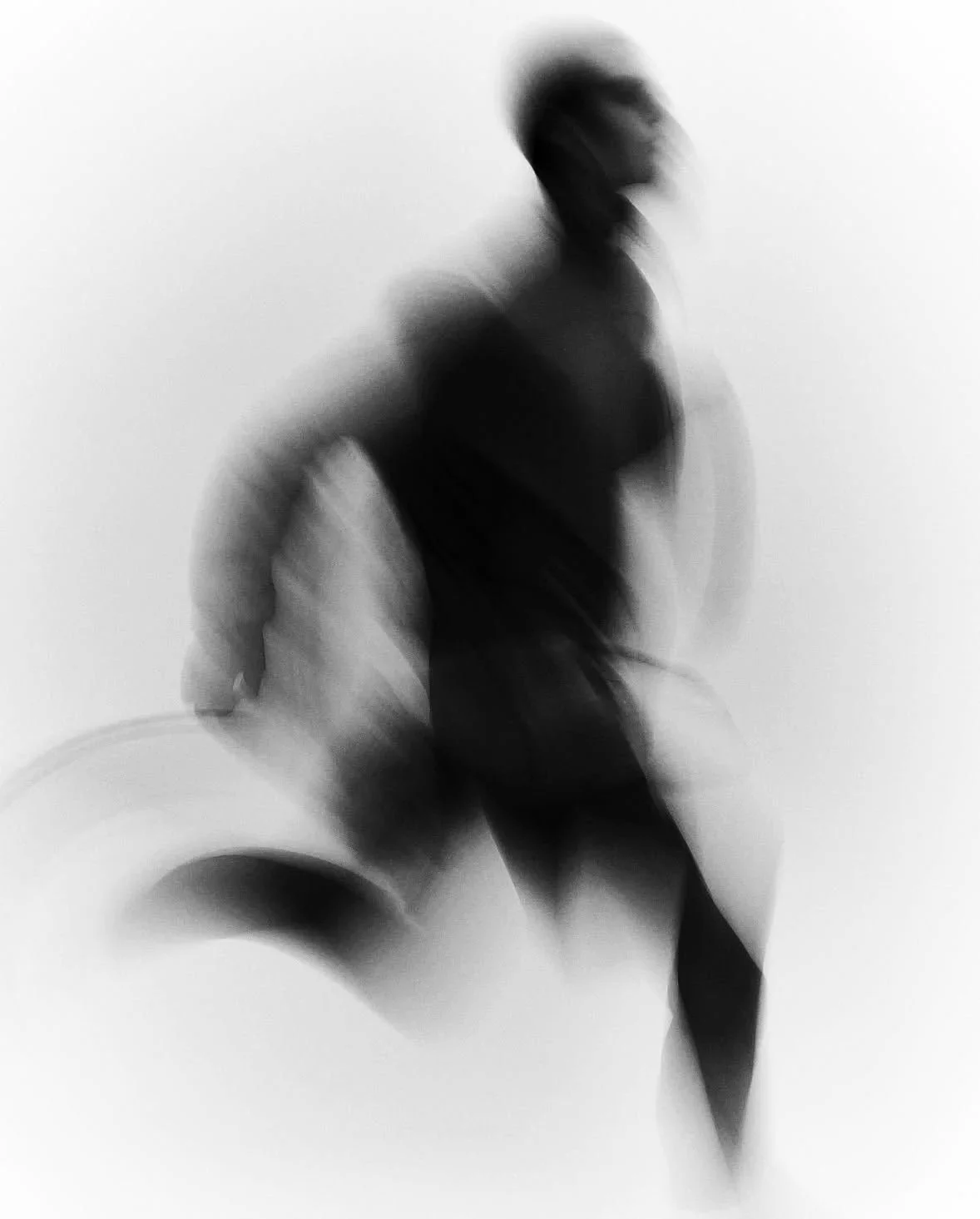 Silhouette floue d'une personne en mouvement, portant un sac, contre un fond blanc.