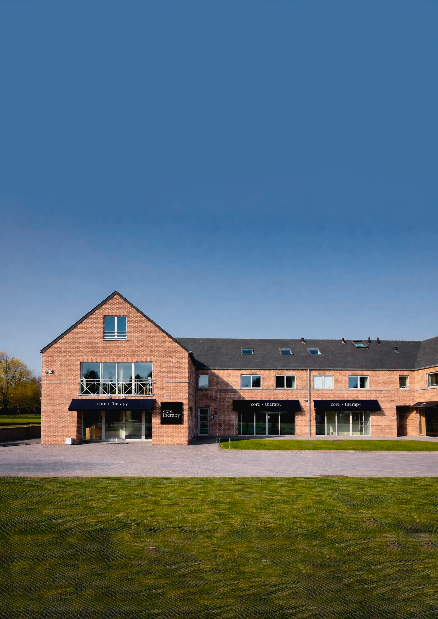 Bâtiment en briques rouges avec des enseignes 'core therapy' sur la façade, sous un ciel bleu clair.