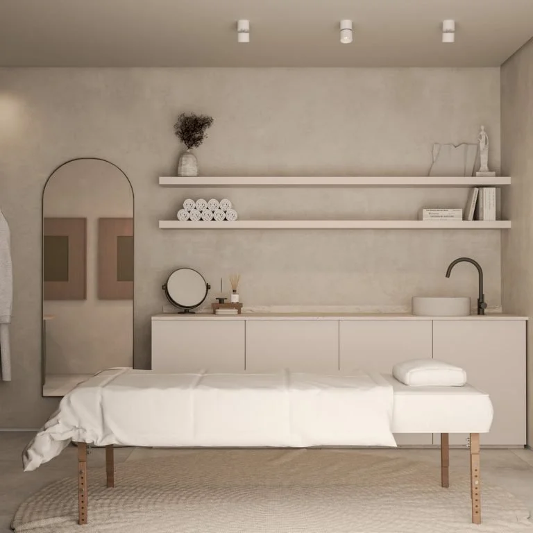 Un environnement intérieur minimaliste avec un lit de massage ou de spa, un miroir, des étagères avec des rouleaux de serviettes, des décorations blanches et neutres, et un lavabo.