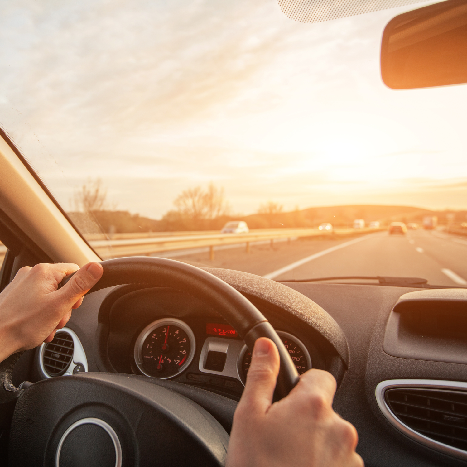 Person kjører bil på motorvei i solnedgang