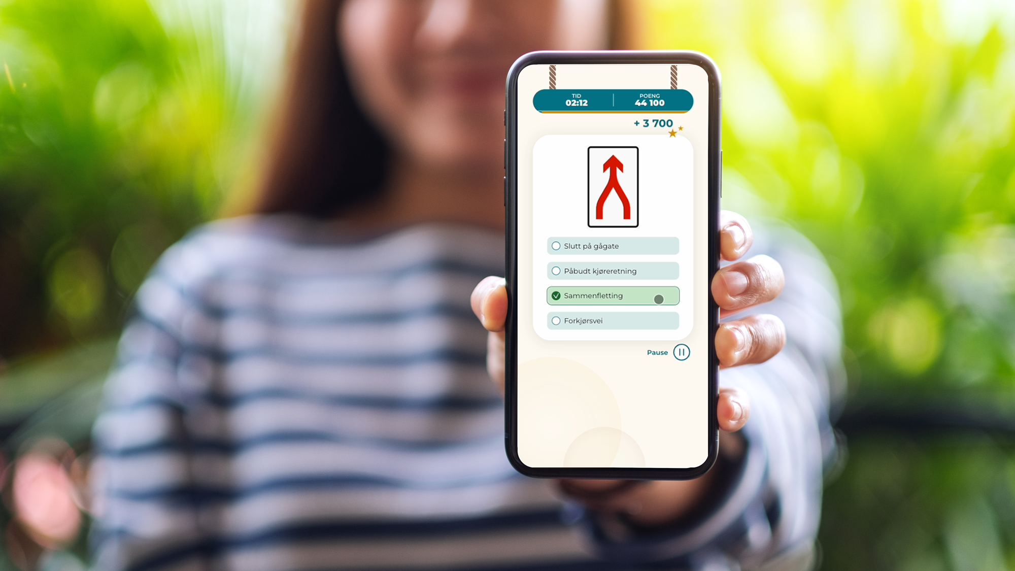 Jente som holder en mobil med trafikkskiltspillet Skiltstorm på skjermen