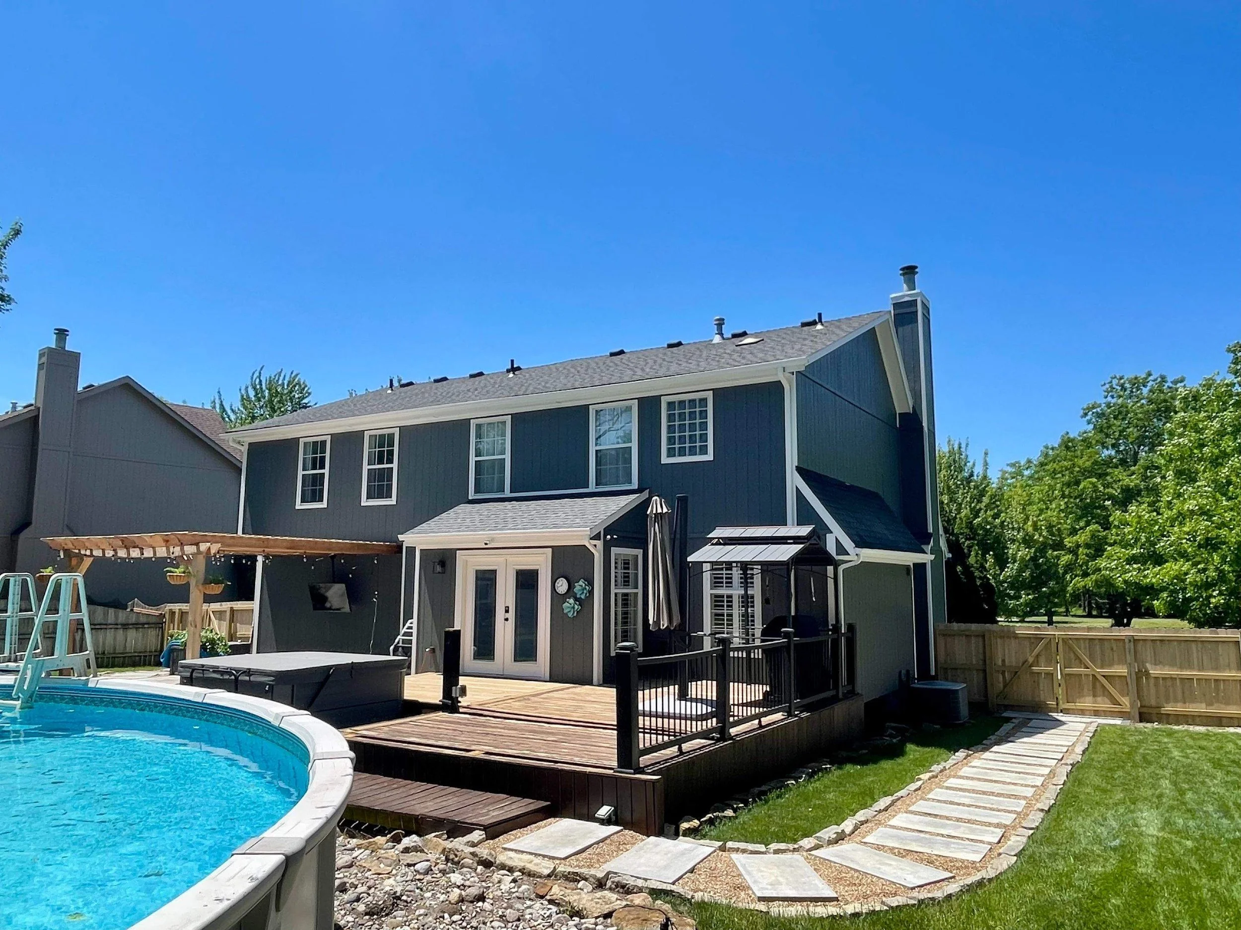 Full exterior repaint in deep blue-gray with crisp white trim — backyard view of a Kansas City home painted by EverPro Painting