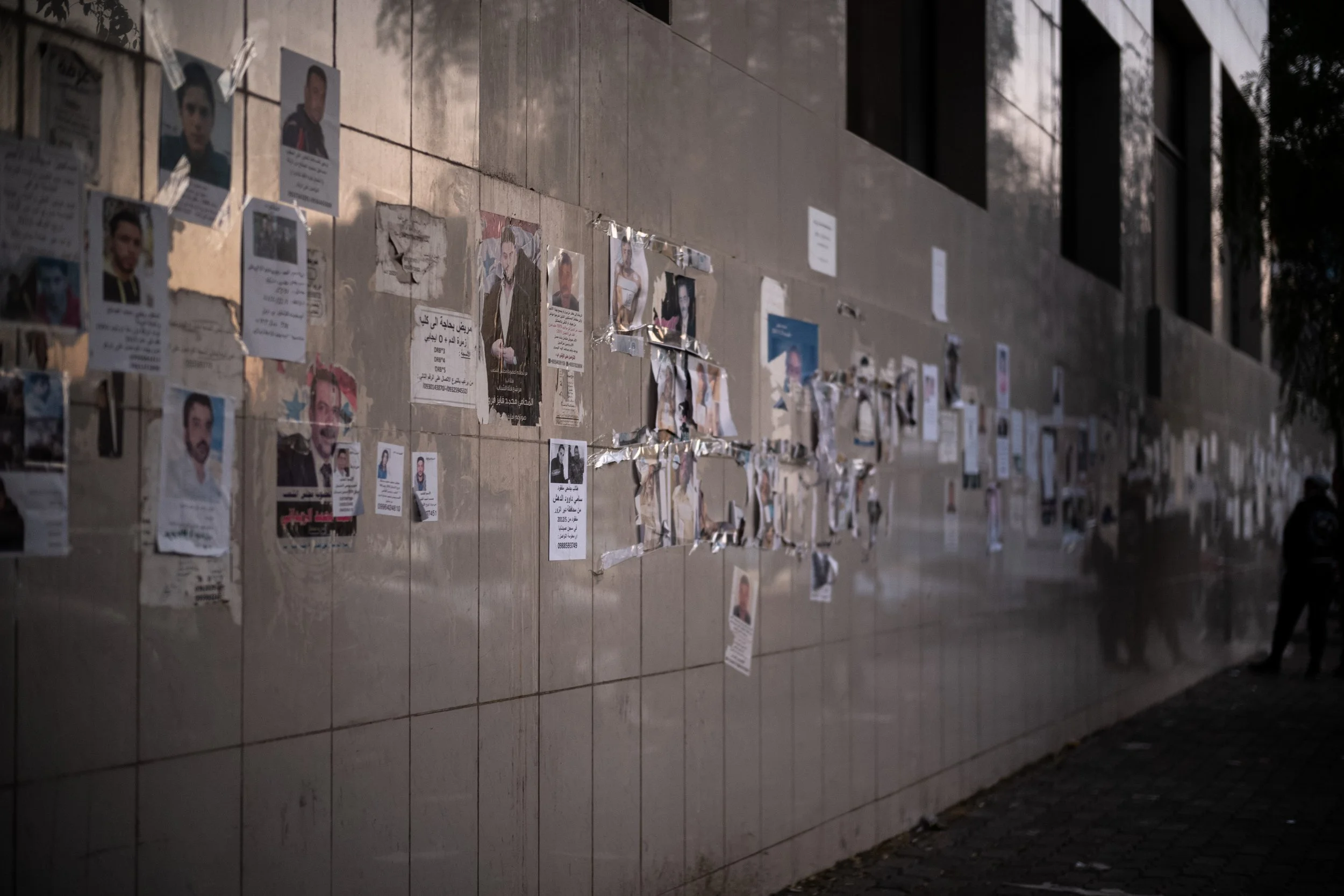 The outer wall of al Mujtahid Hospital in Damascus is covered with hundreds of portraits of missing persons and bodies undergoing identification. Damascus, Damascus, Syria, 15 December 2024.  © Audrey M G, SpectoMedia.