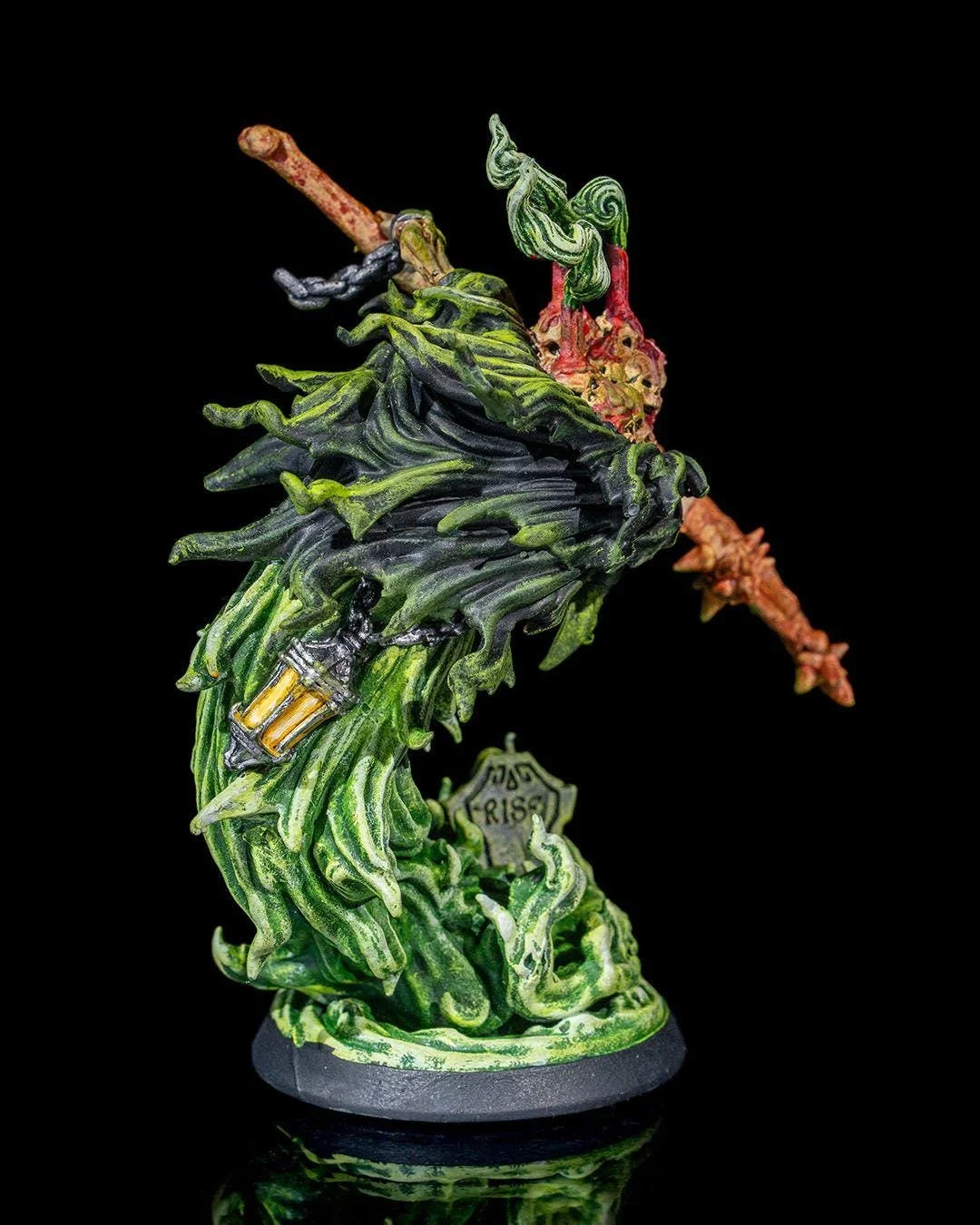 A detailed miniature sculpture of a leafy, green character with a torch, set against a black background.