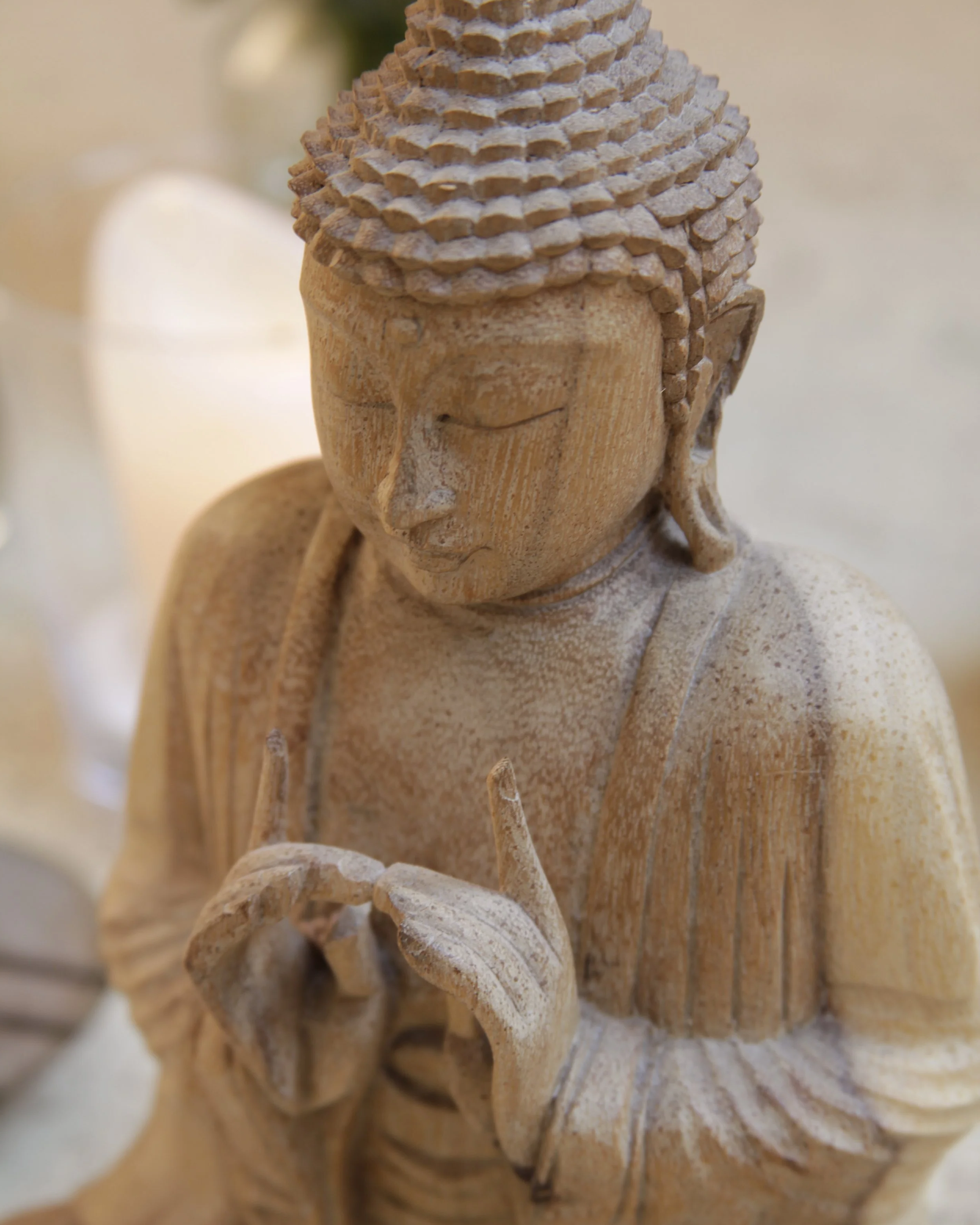 Nahaufnahme einer geschnitzten Holzstatue eines meditierenden Buddha mit geschlossenen Augen.