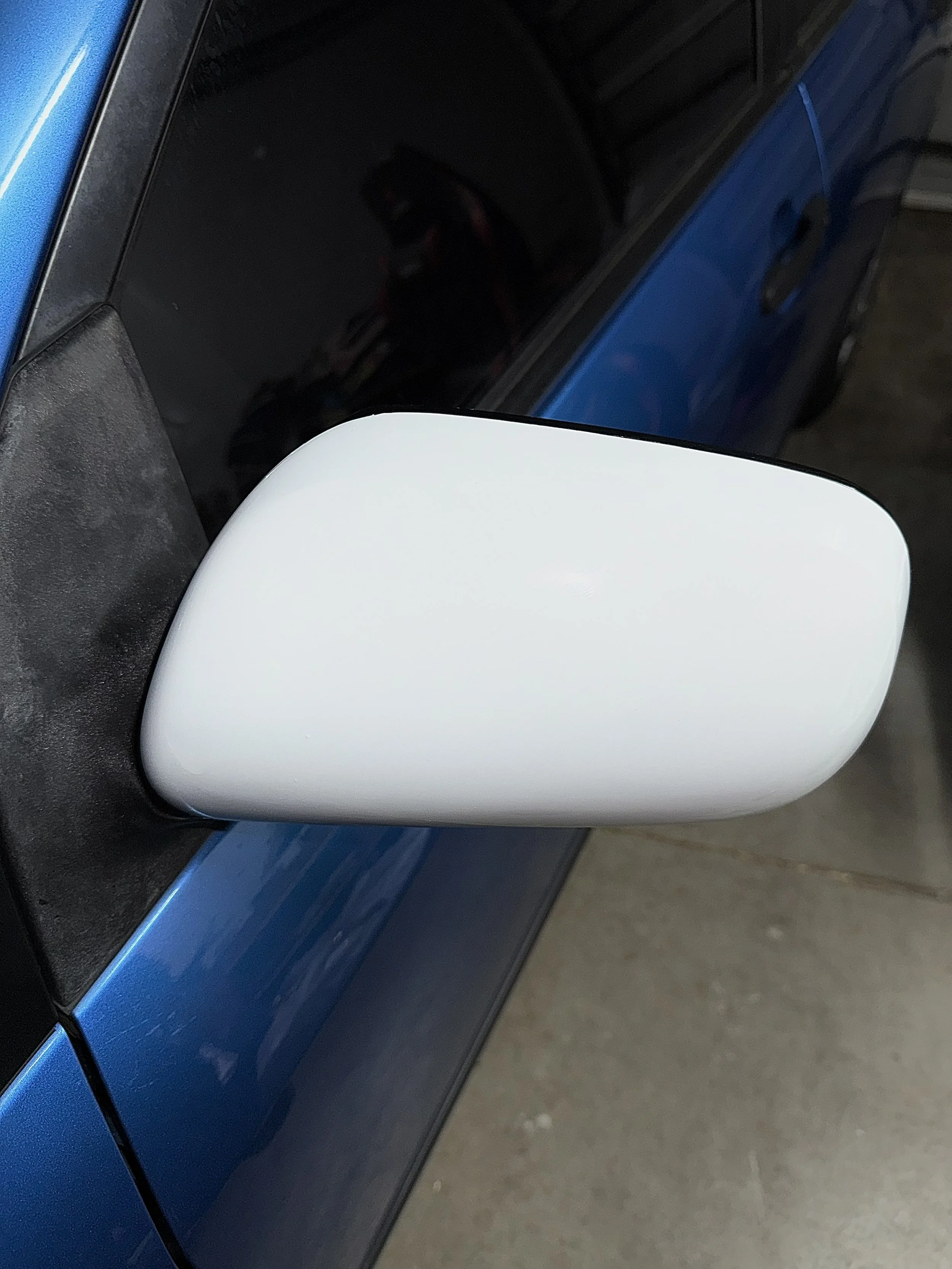 Close-up of a vinyl wrapped white side mirror on a blue vehicle.