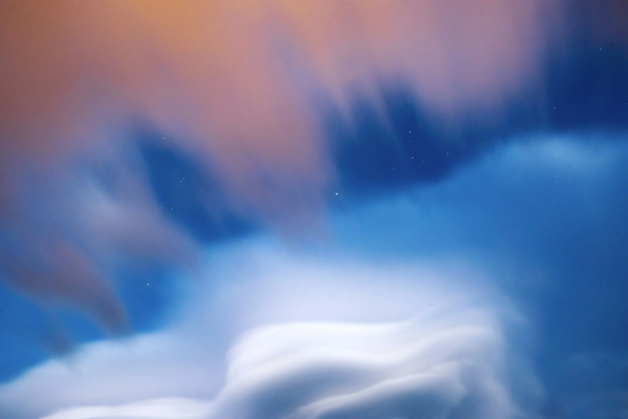 Abstract view of the sky with clouds and stars, displaying shades of pink, purple, and blue.