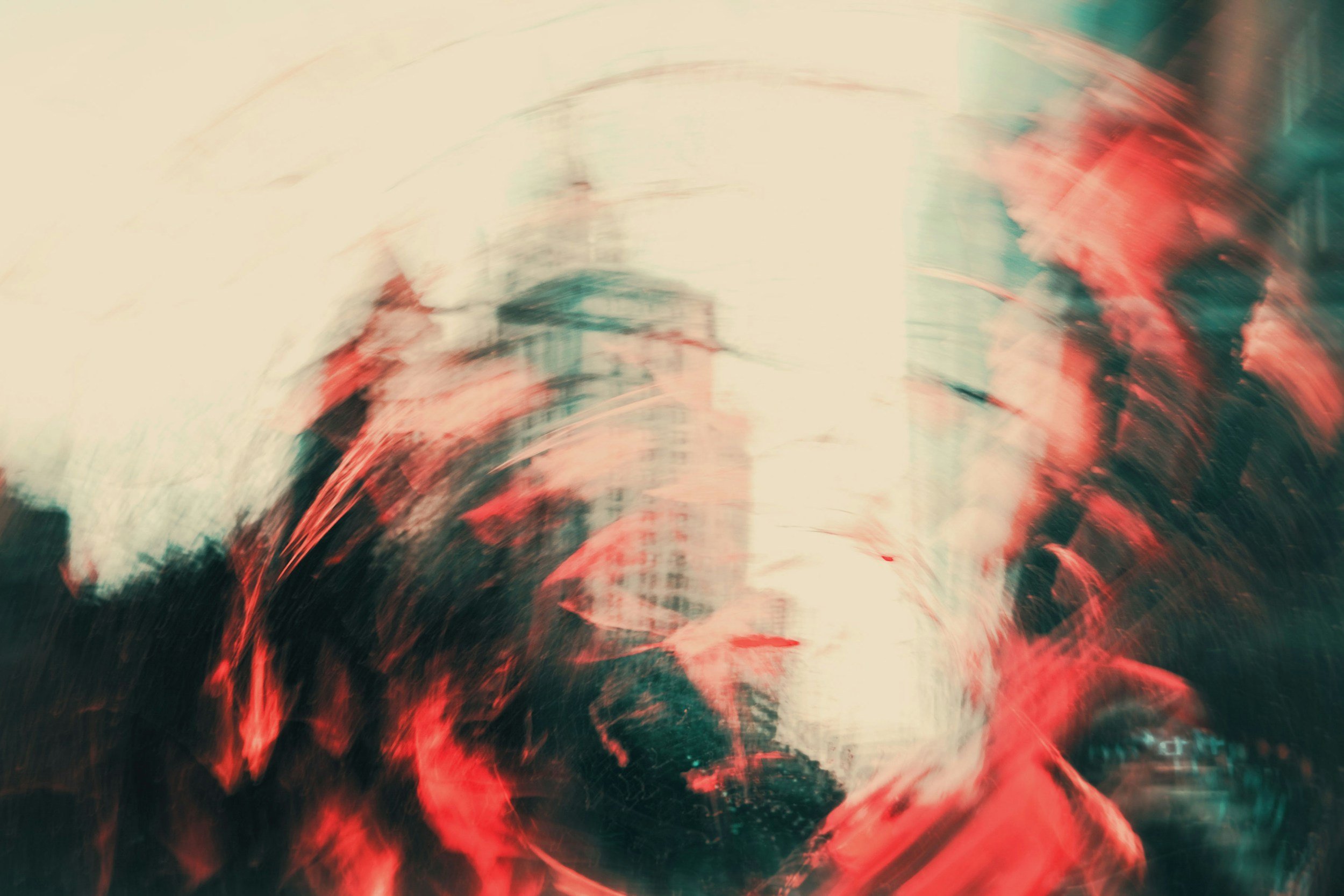 Abstract image created using double exposure featuring a whirl of reds, greay, deep greens and beige