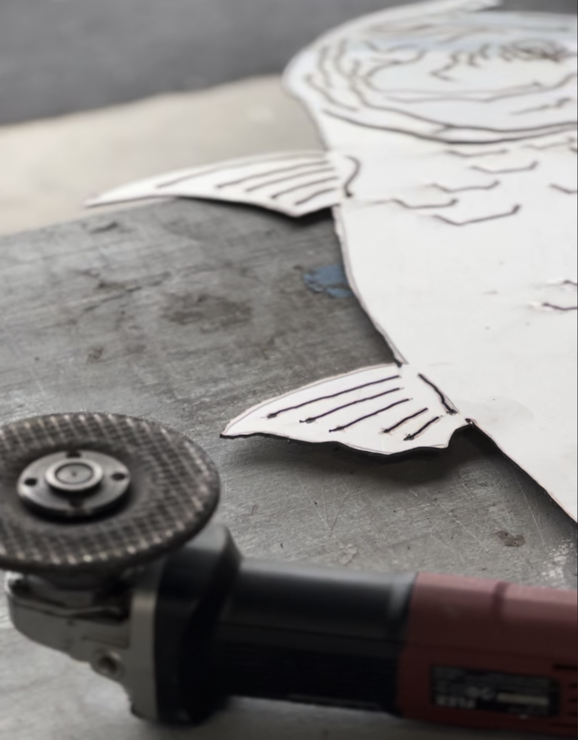 Close-up of paper with a sketched face and a rotary tool on a work surface.