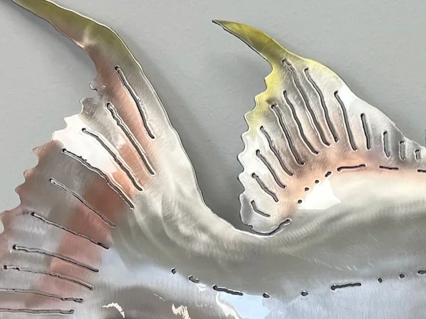 Close-up of a metallic abstract sculpture resembling swirling or curling leaves or fins.