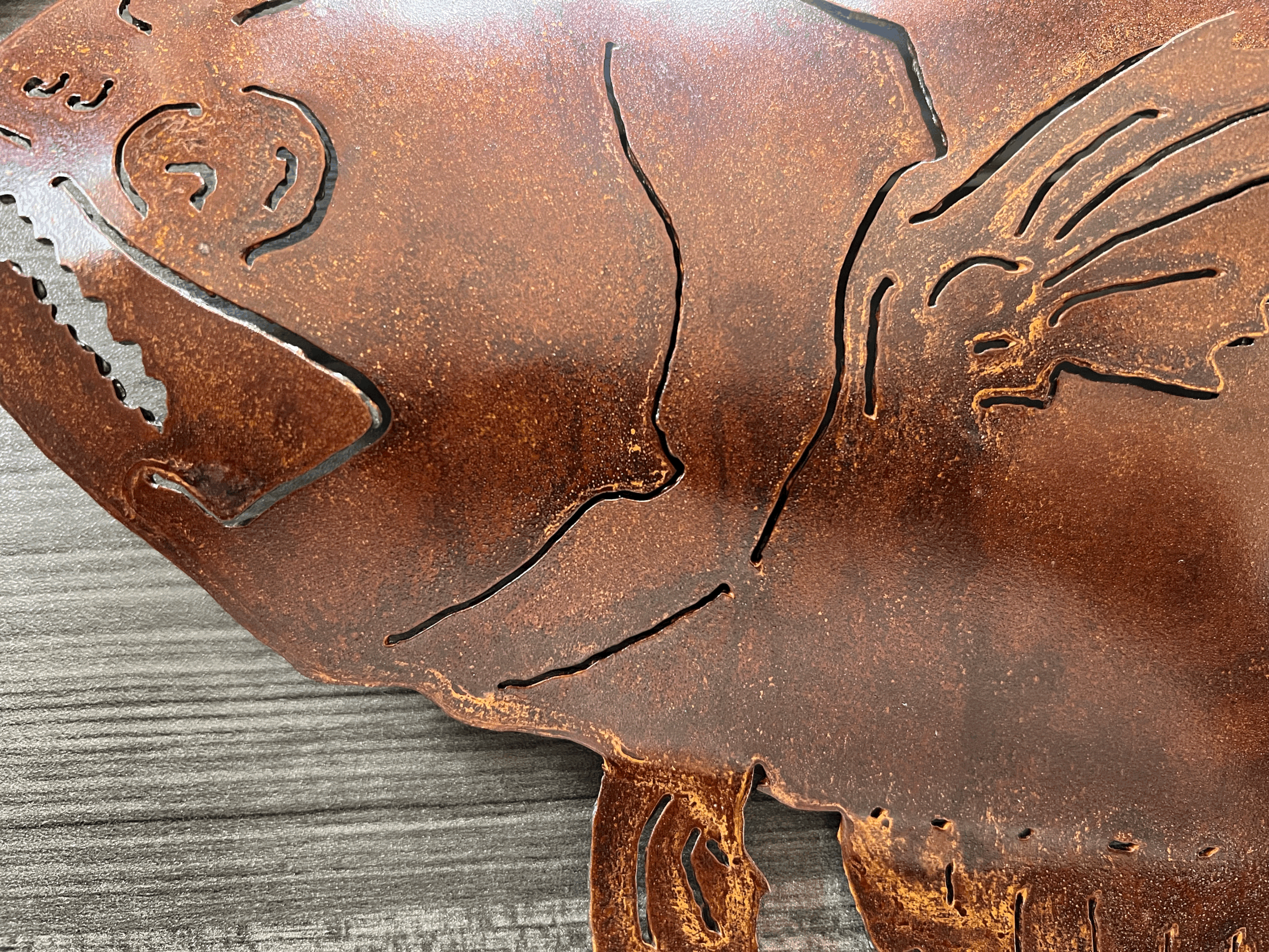 Close-up of a rusted metal sculpture depicting two faces in profile looking at each other, with intricate line details.