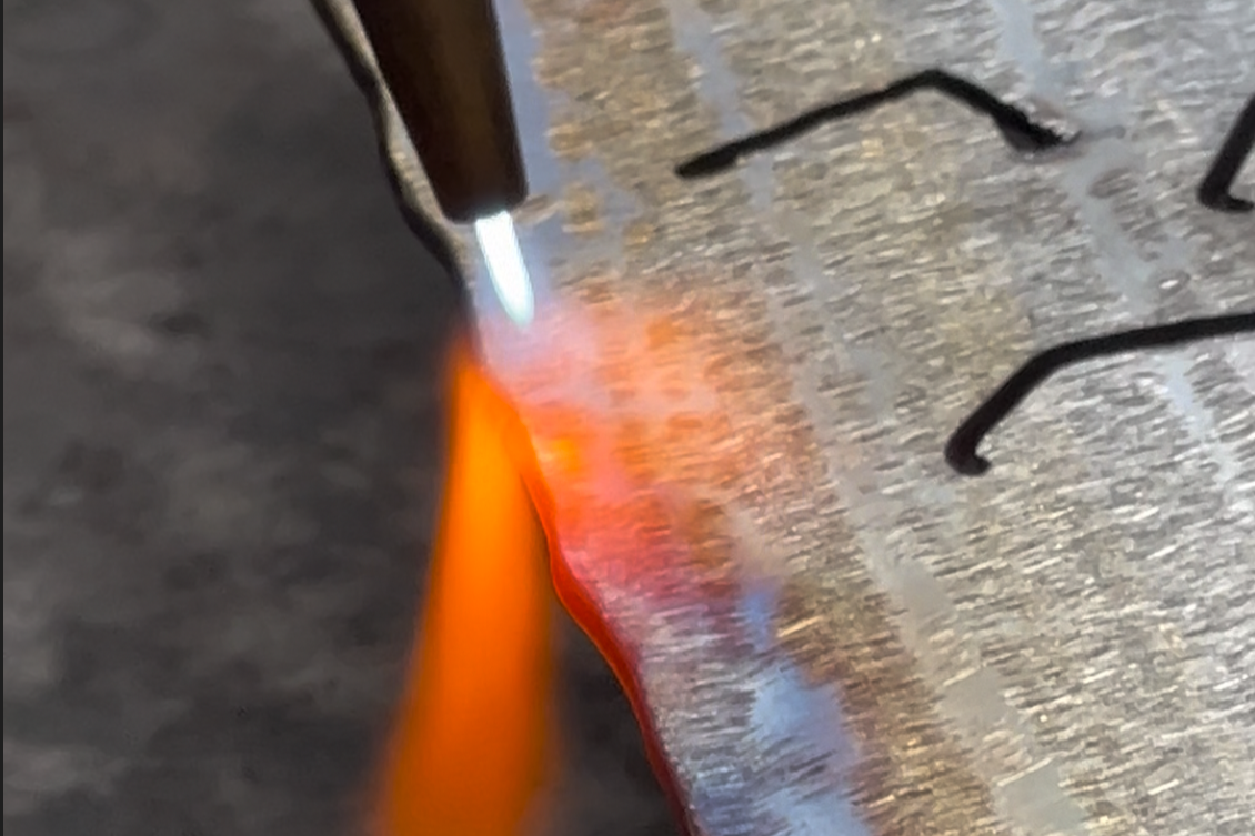 A soldering iron applying heat to a metal circuit board with electronic components.
