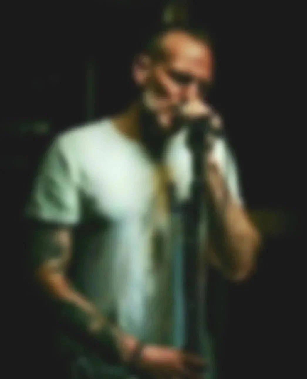 A man with a ponytail singing into a microphone in a music venue.