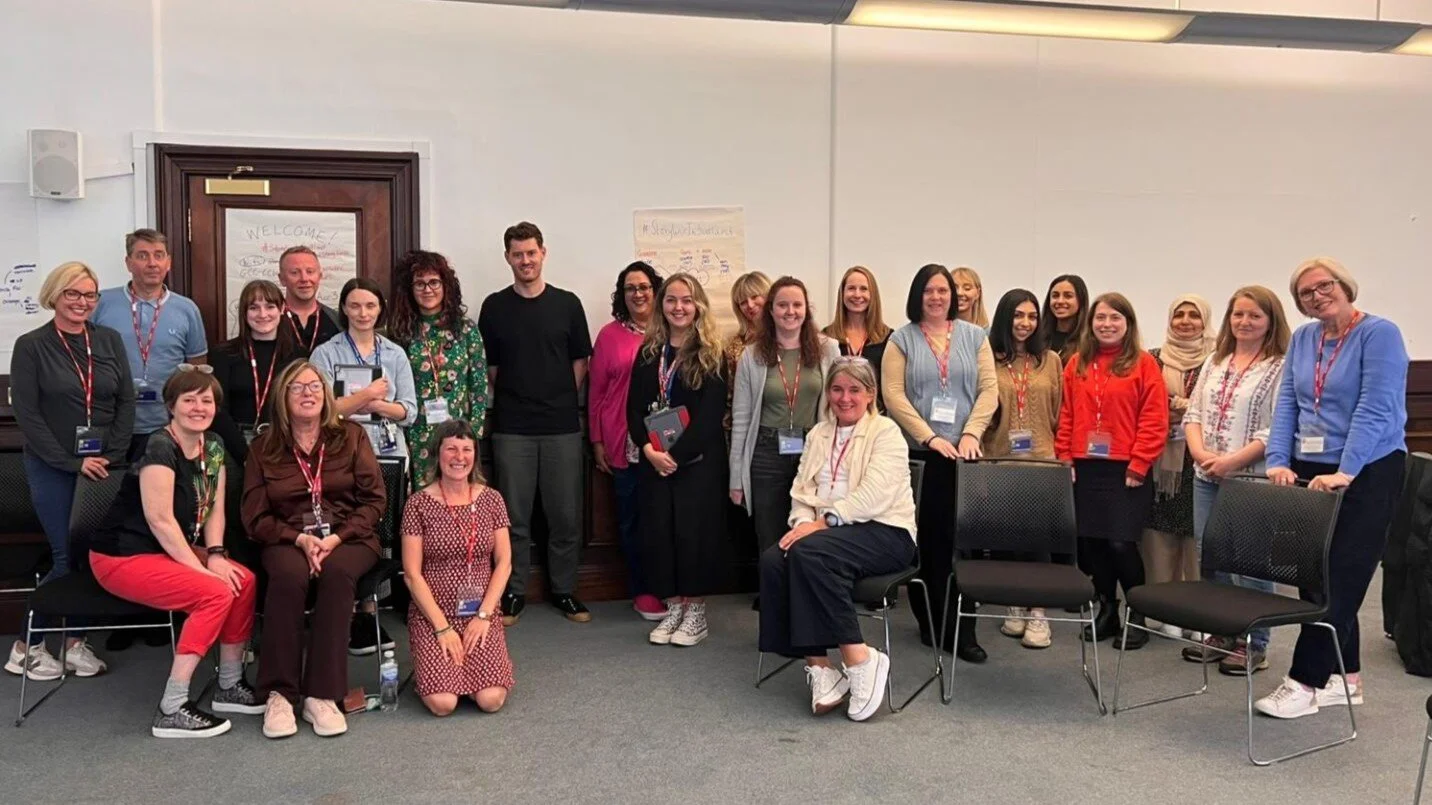 Photo of people gathered in a conference room for a group photo.