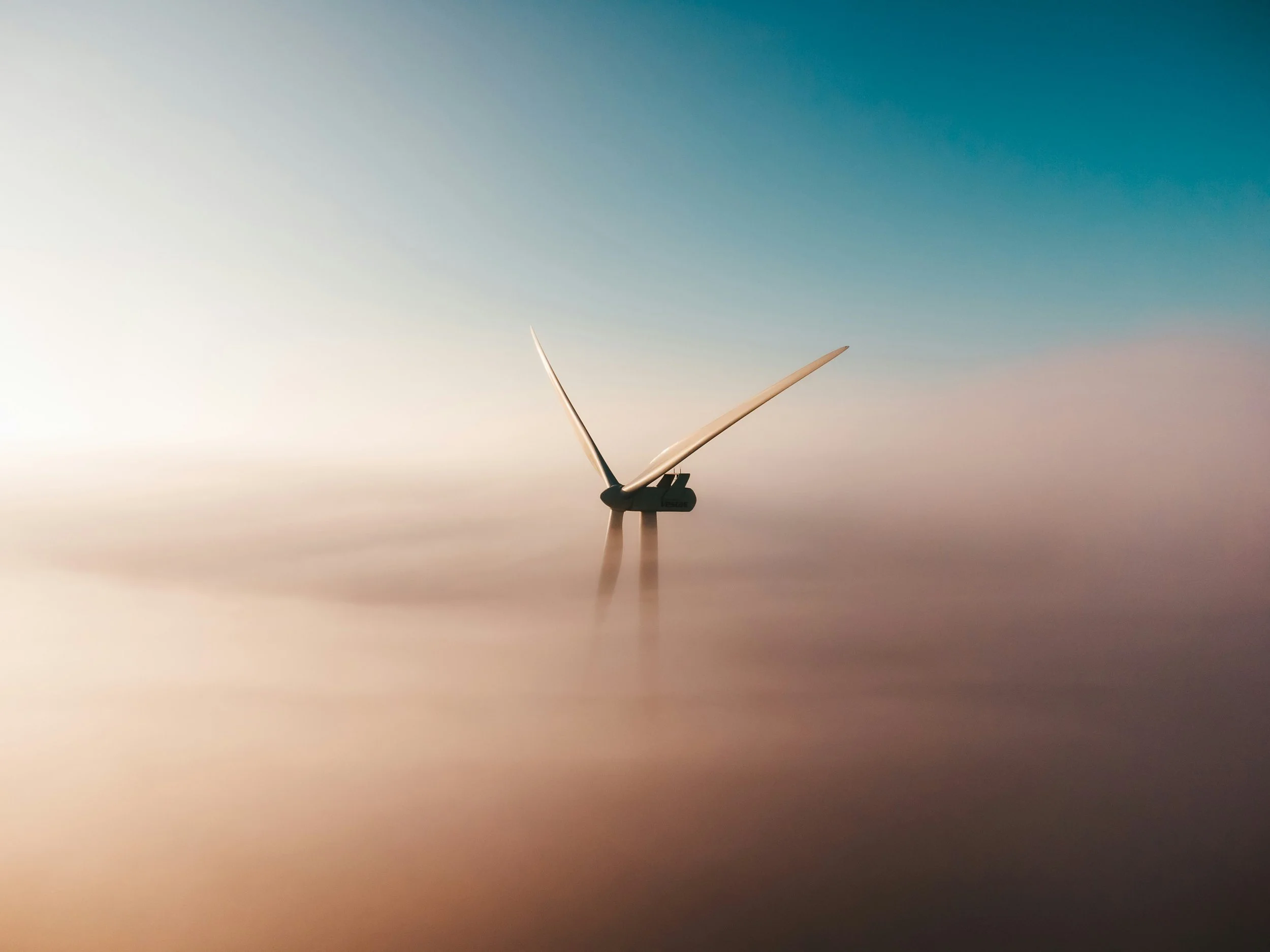 A wind turbine standing in the ocean, with a cloudy sky at dawn or dusk, creating a serene and minimalist scene.