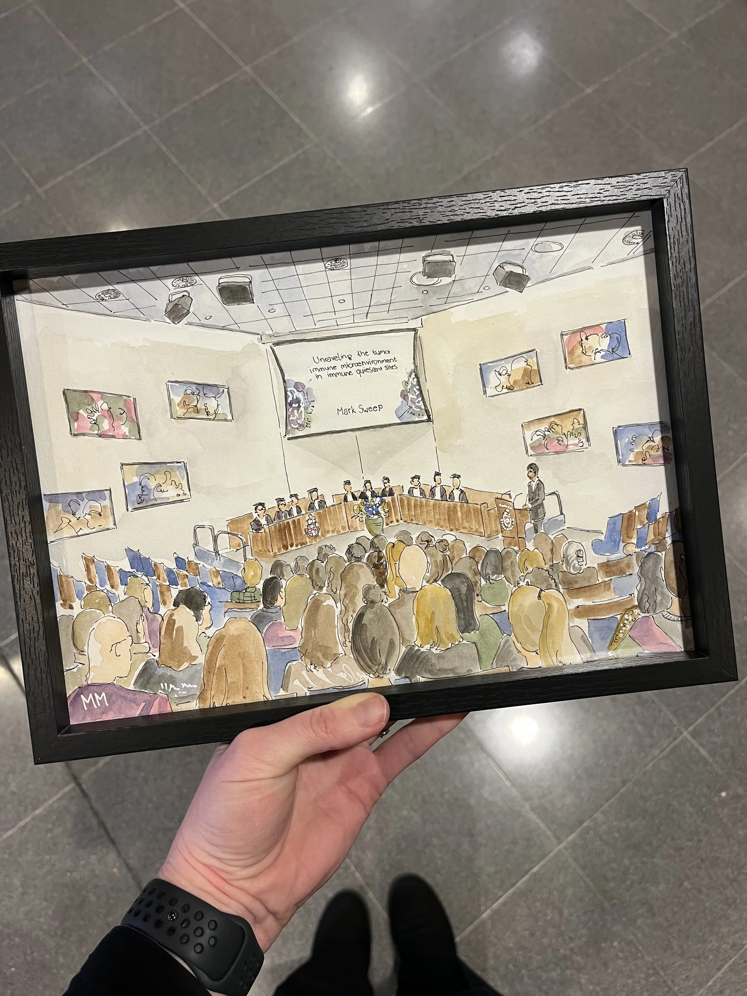 Een nagebootst schilderij van een conferentie met een publiek, een panel van sprekers, en een scherm met tekst, binnen een kunstmatige kader vastgehouden door een persoon.