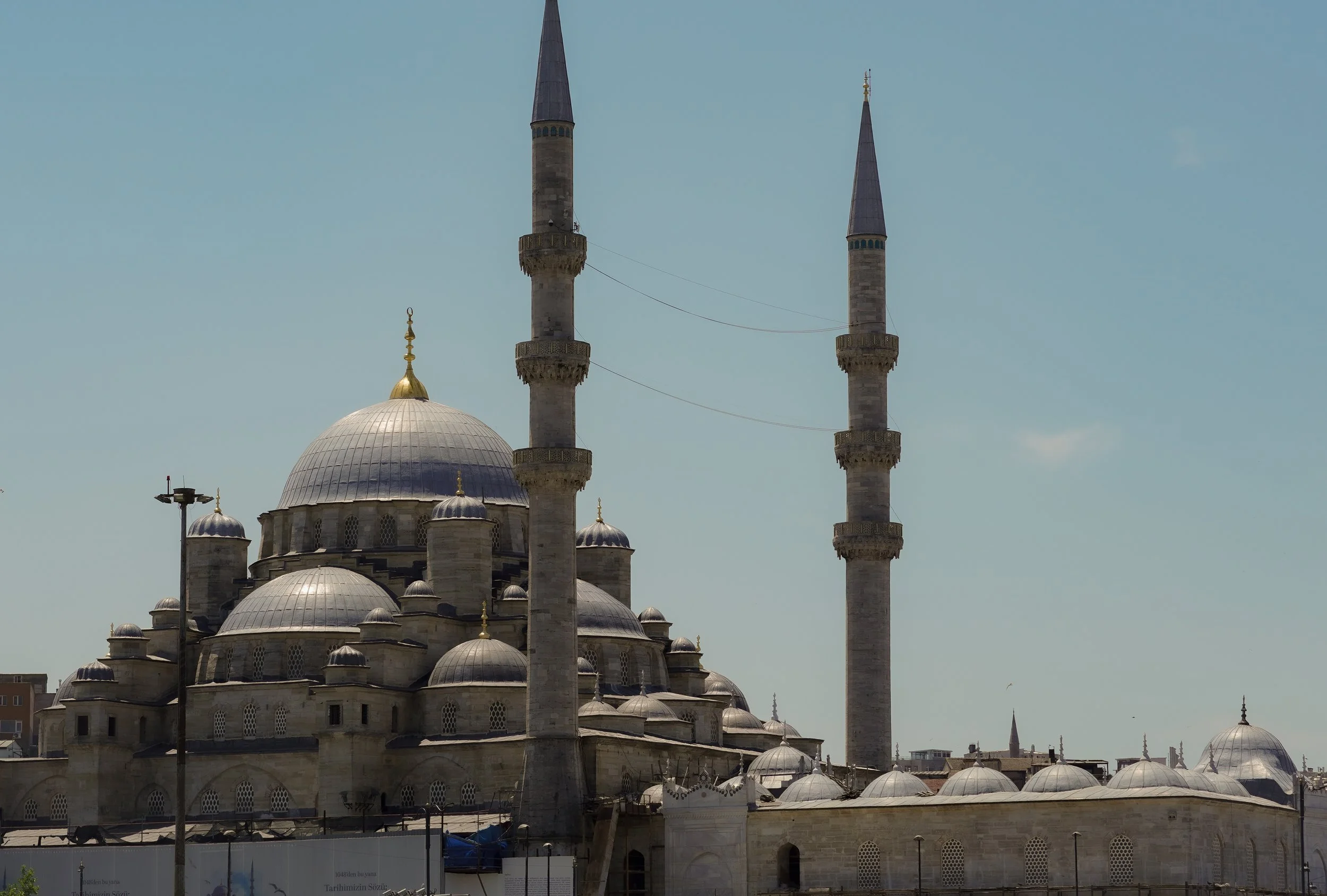 Eine Moschee mit mehreren Kuppeln und zwei hohen Minaretten unter einem blauen Himmel