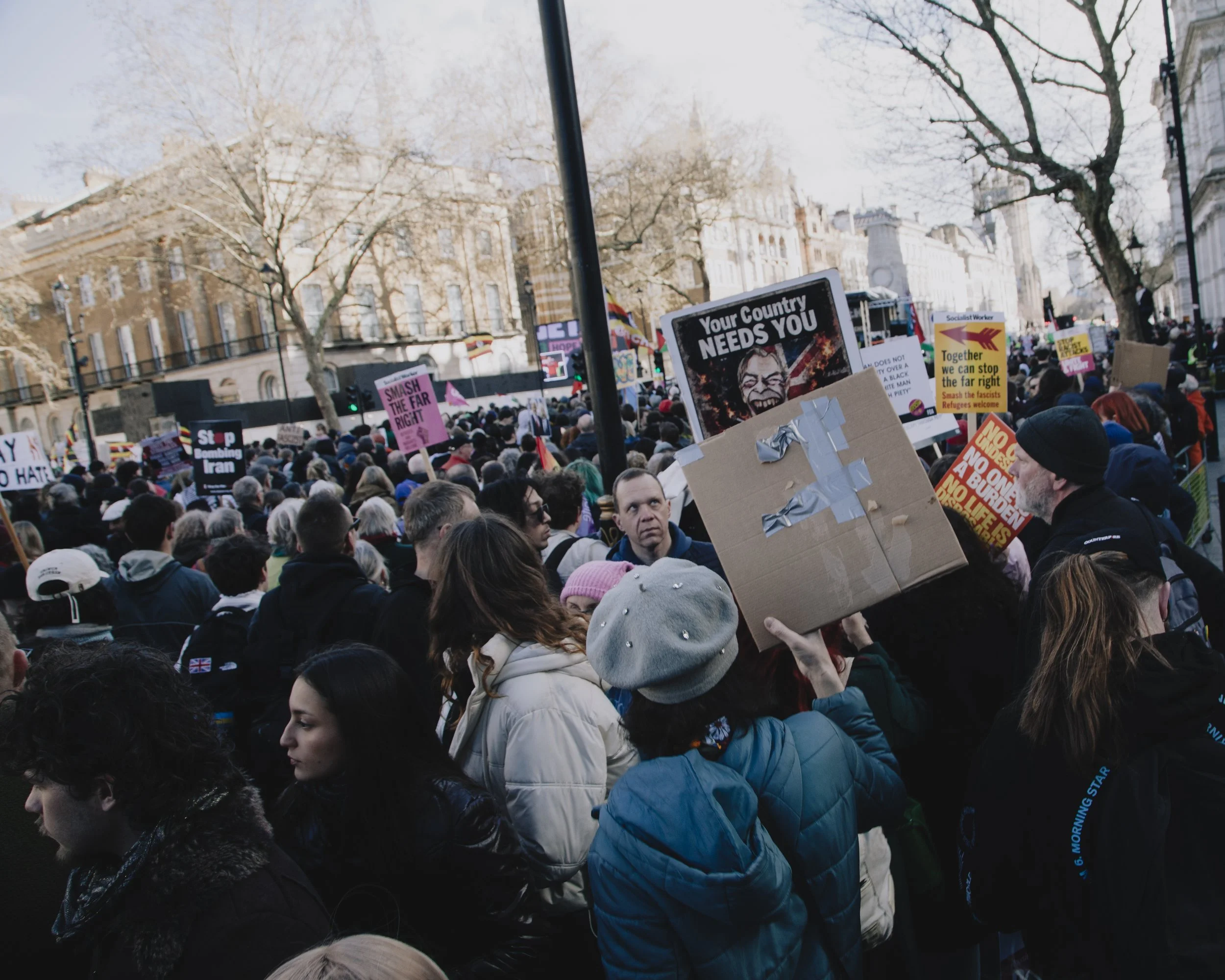 Man stares at Farage placard whilst passing through demonstration. Together Against the Far-Right Demonstration, London, UK.