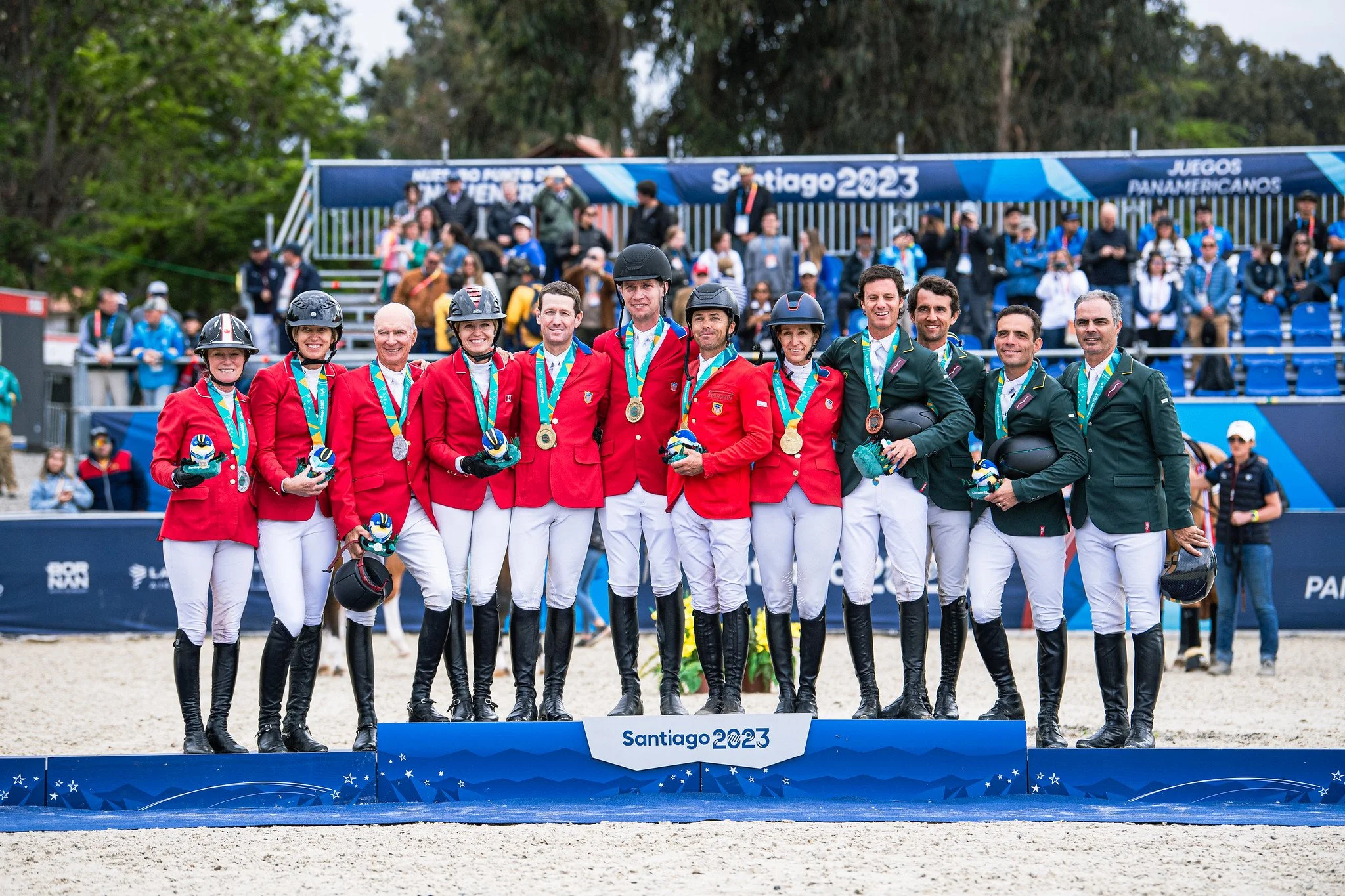 Equestrian team in medals posing on winners' podium at Santiago 2023 equestrian event.