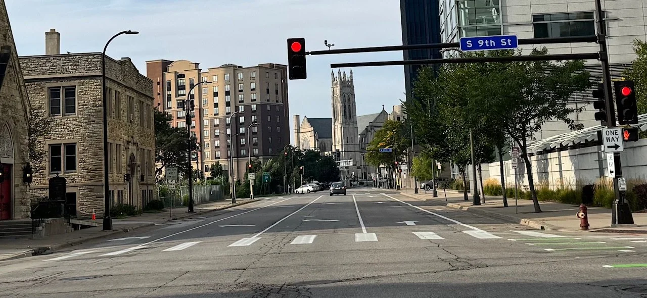 Downtown Minneapolis street view with buildings, traffic lights, and a church in the background at the intersection of South 9th Street.
