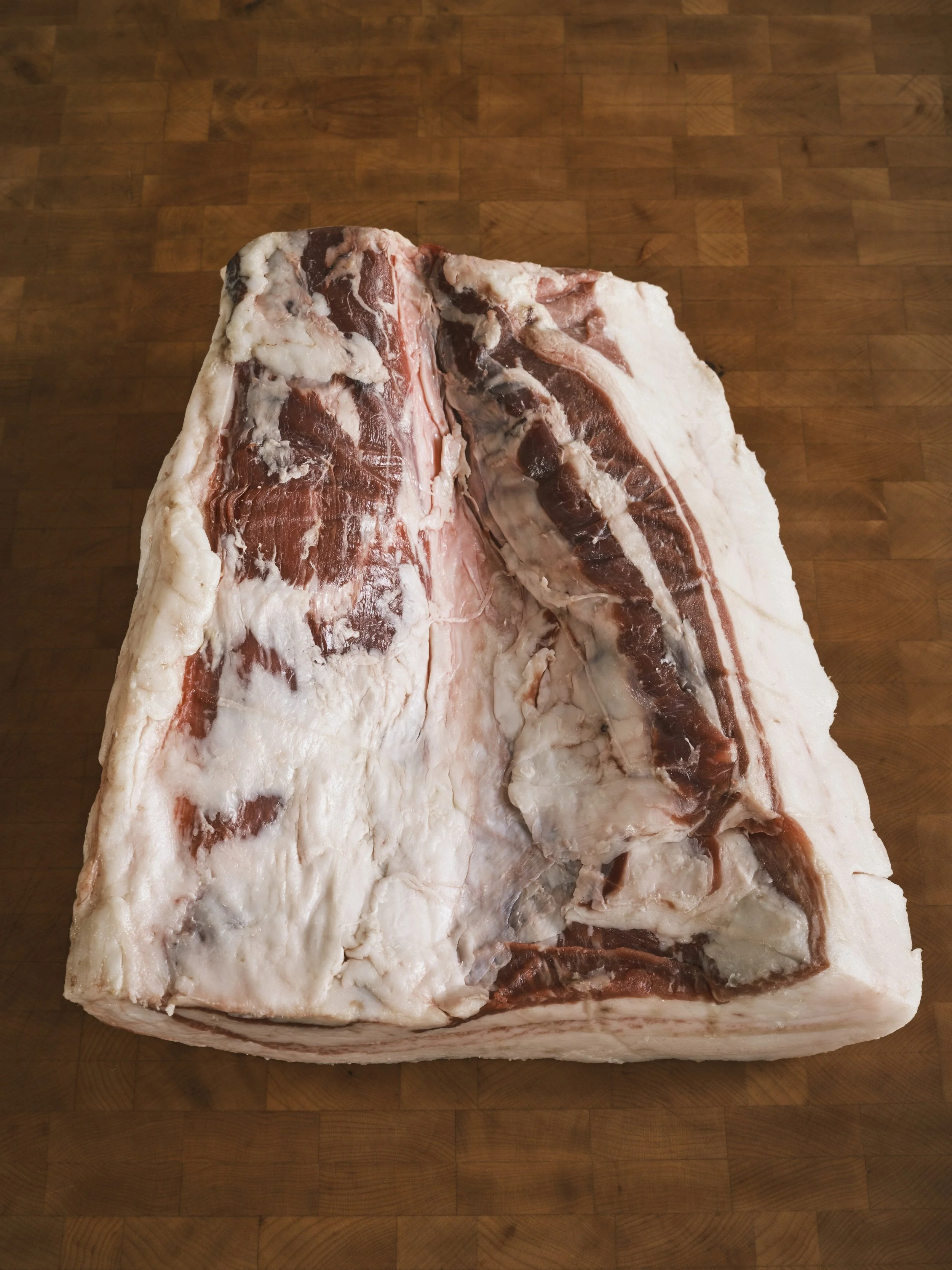 Large cut of raw beef brisket on a wooden surface.